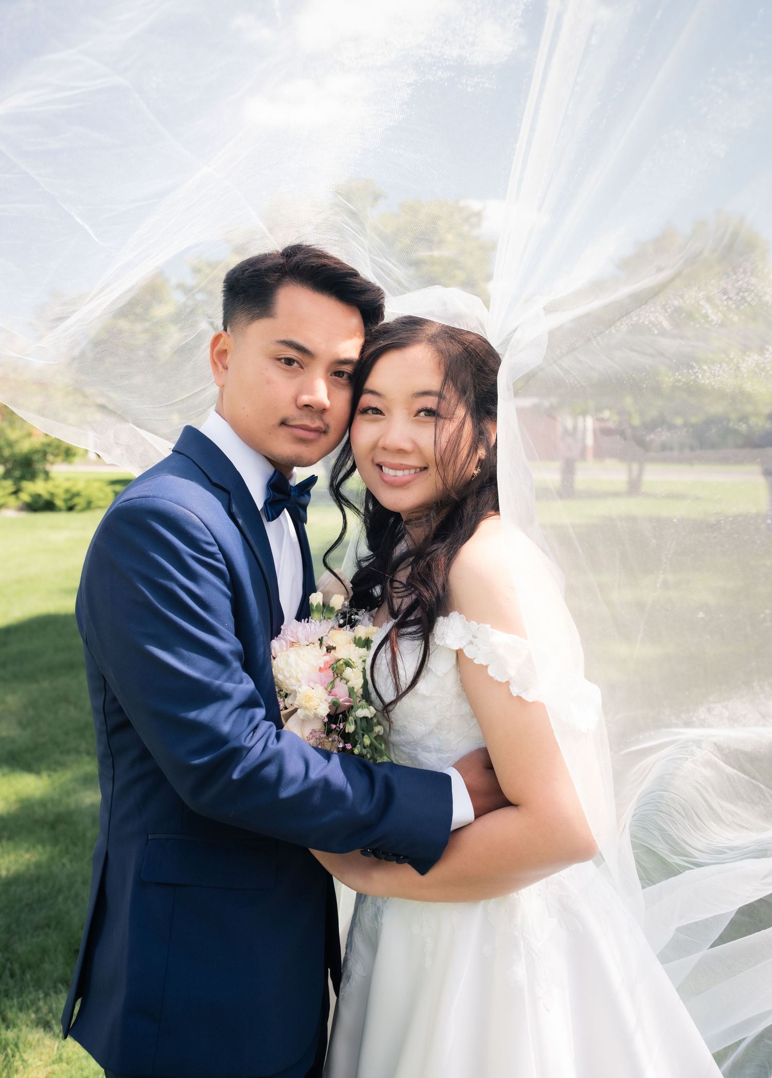 Romantic wedding portraits with flowing veil in outdoor garden setting.