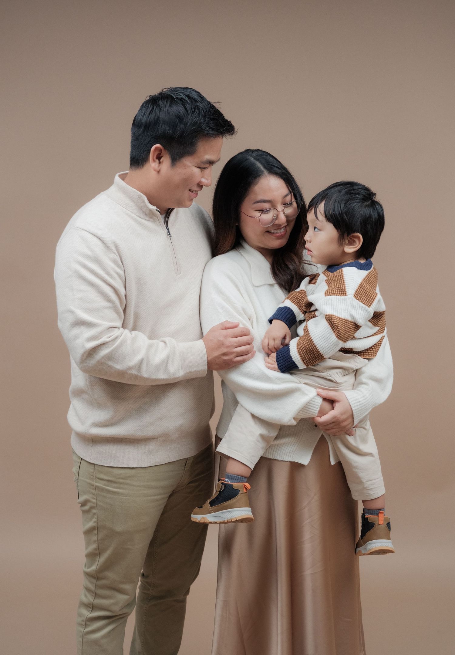 Tender family moments captured in studio with coordinated cream and beige outfits.