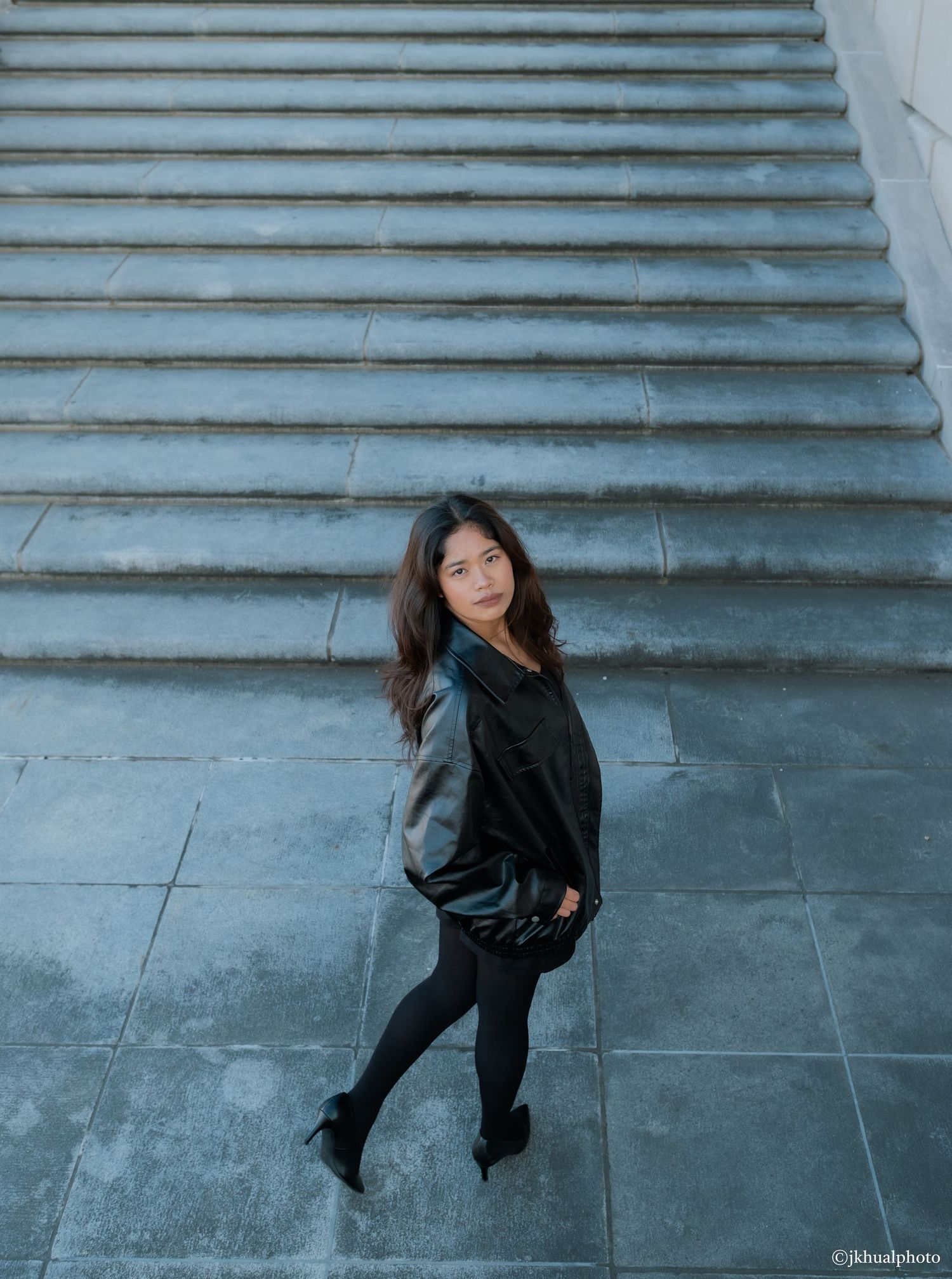 A sequence of artistic photos showing a person in black clothing spinning and dancing on concrete steps with a blue wall.