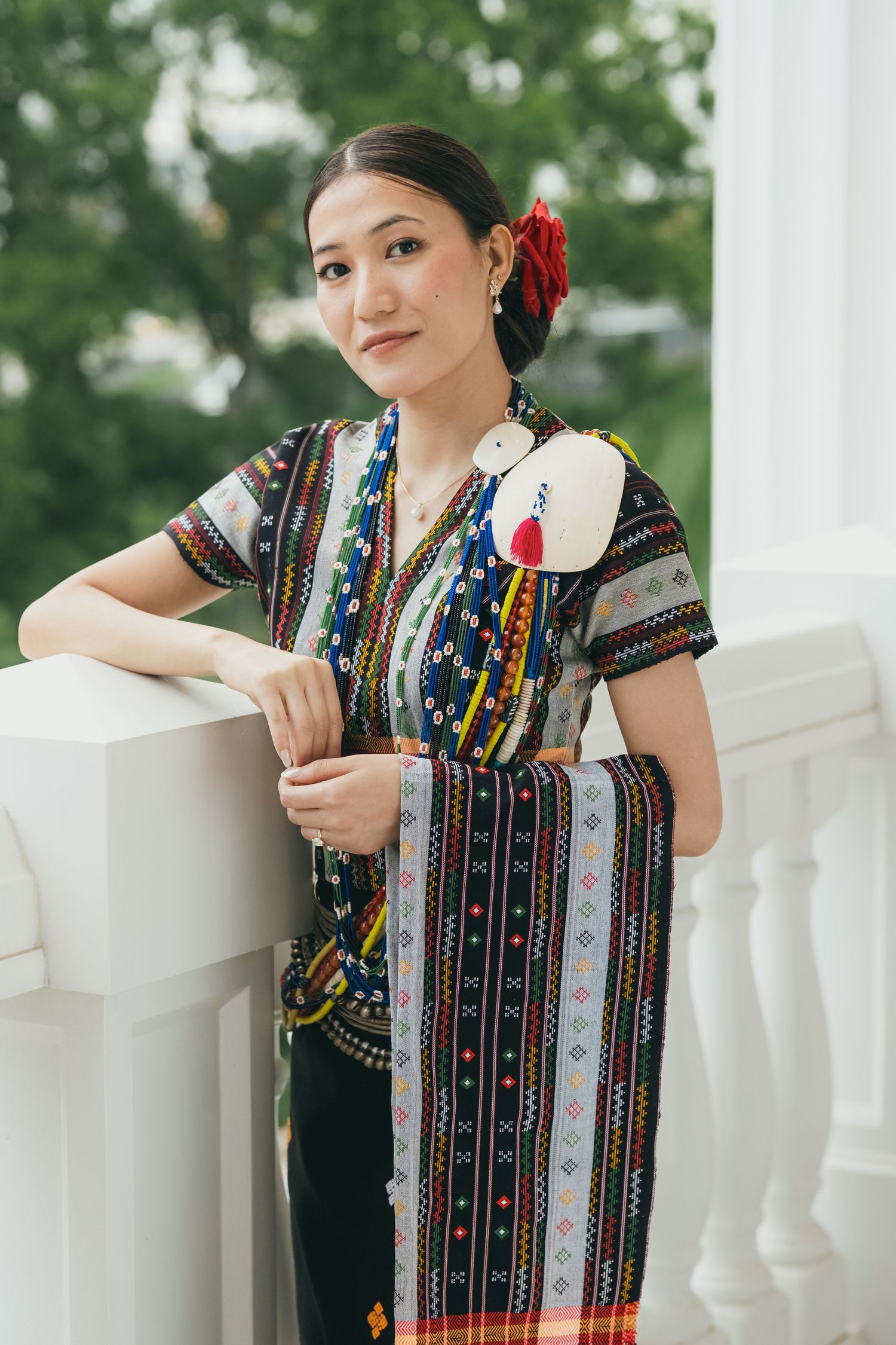 Elegant traditional dress with beaded necklaces and embroidered details captured in outdoor setting.