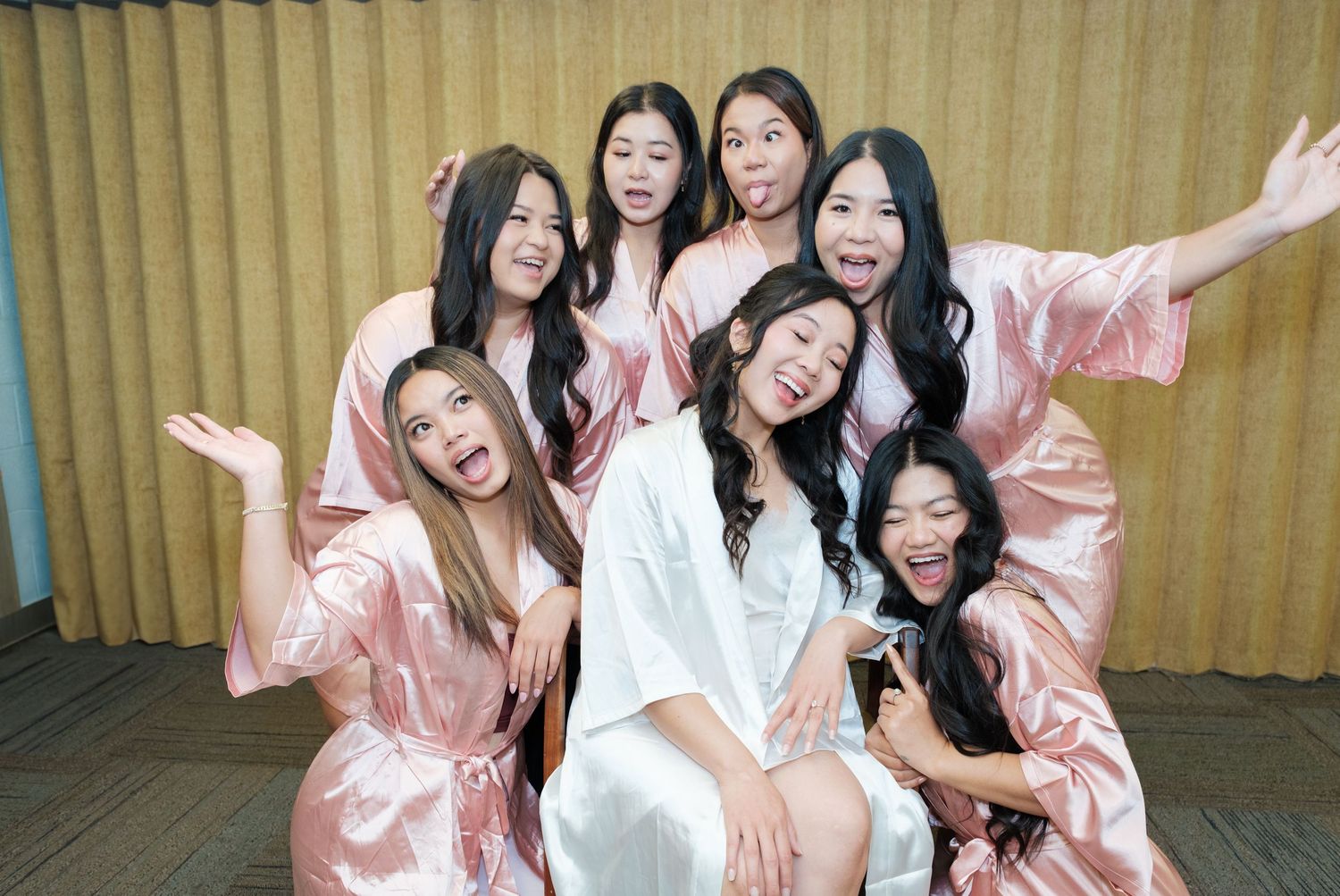 Wedding party in matching pink robes sharing candid moments together.