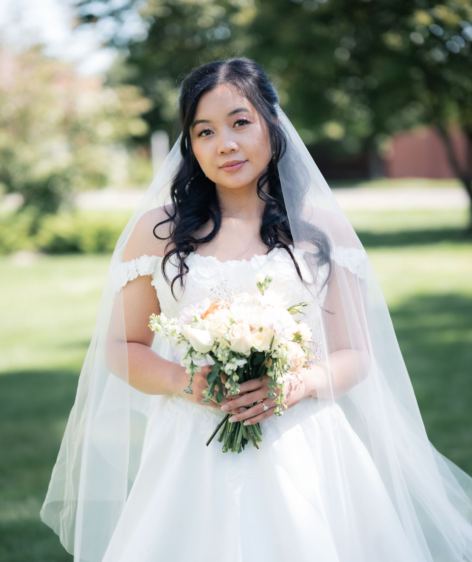 Classic bridal portrait outdoors featuring white wedding dress, veil and neutral bouquet.