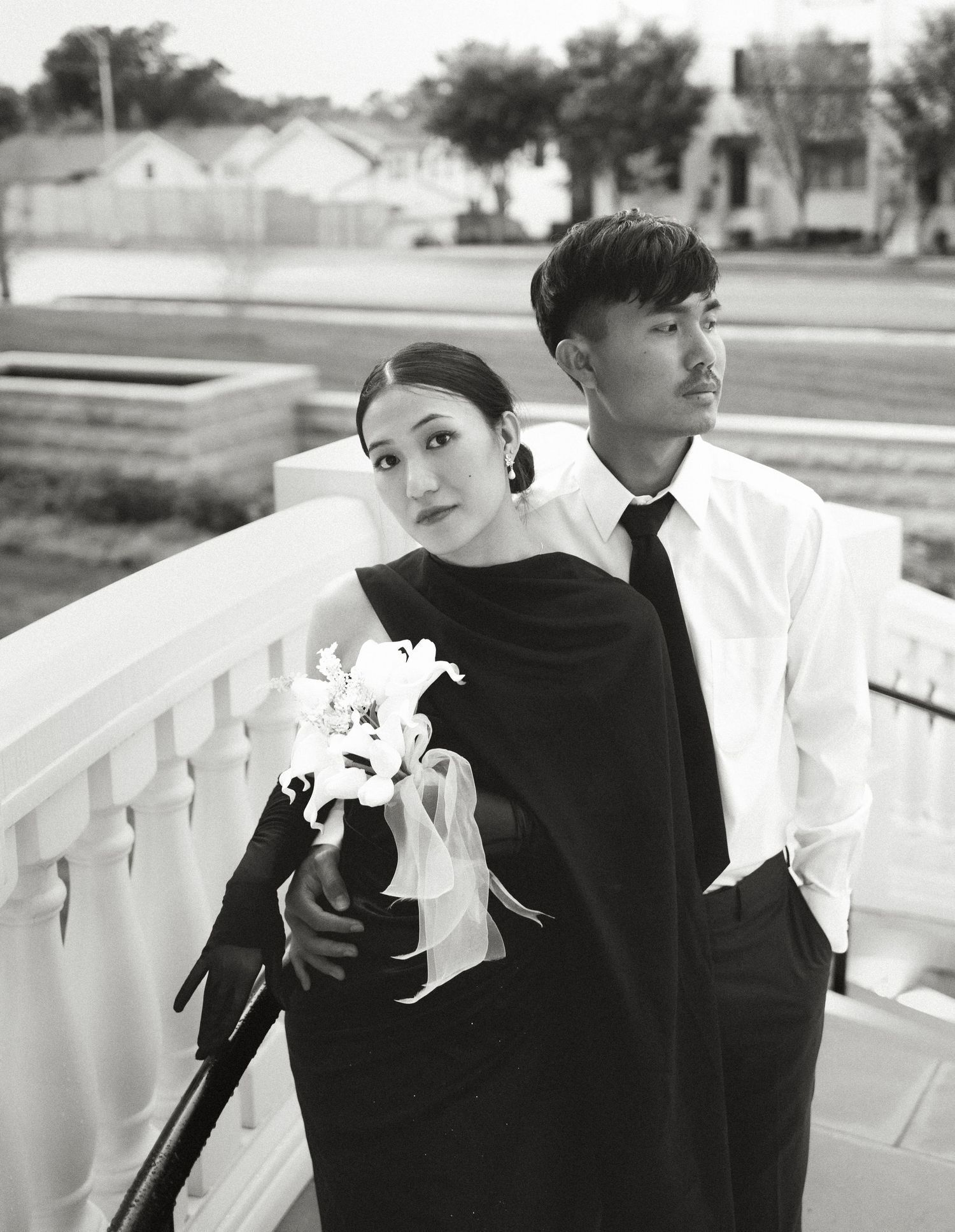 People in black and white outfits pose along a white railing outdoors.