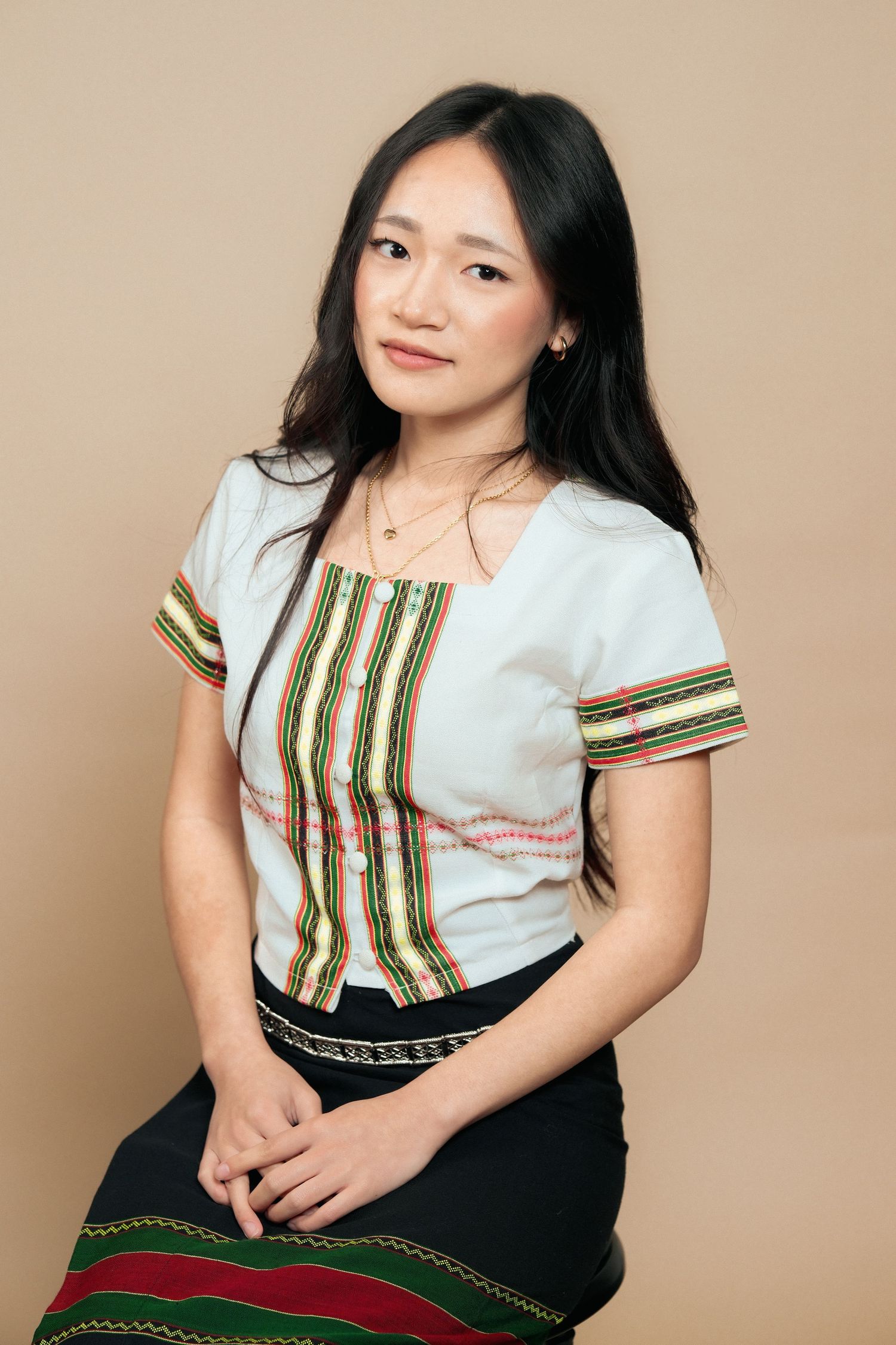 Studio portrait showcasing traditional white and striped ethnic clothing.