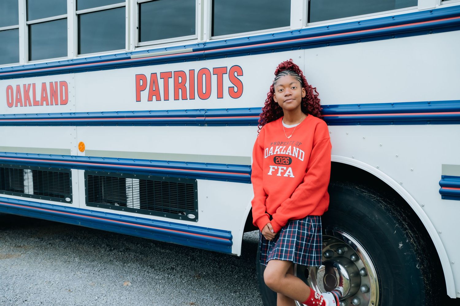 Student in red Patriots sweatshirt poses in front of school building.
