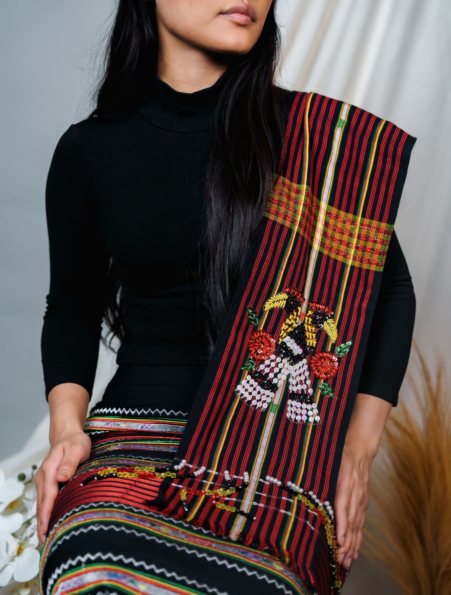 Close-up detail of intricate red and black woven textile with geometric patterns.