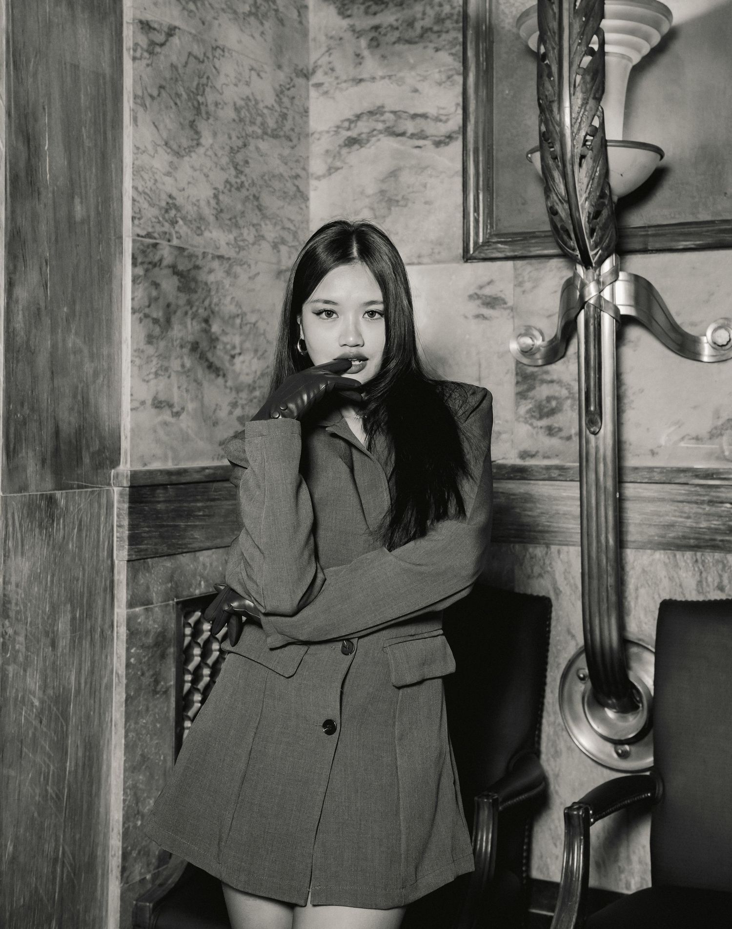 A series of four black and white photos showing someone in a blazer posing against a textured wall.