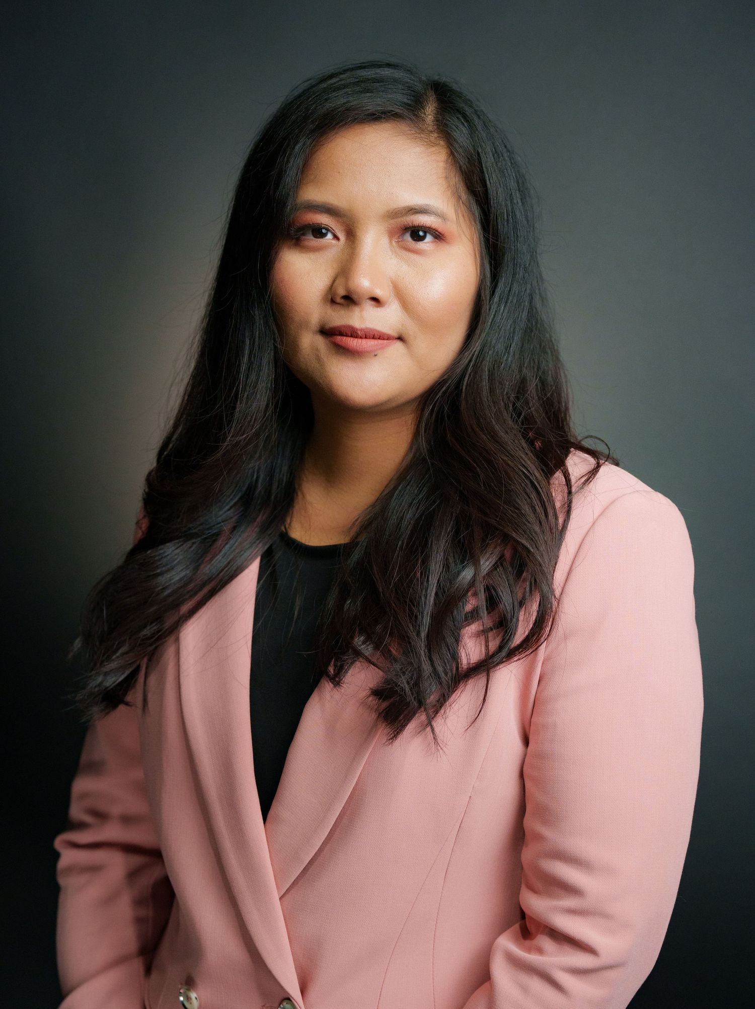 Professional headshots of woman in pink blazer against dark background.
