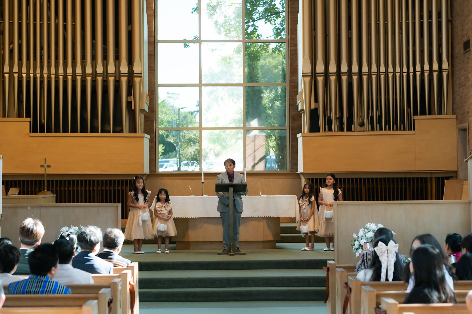 A church congregation watches a choir performance near a pipe organ during a religious service.