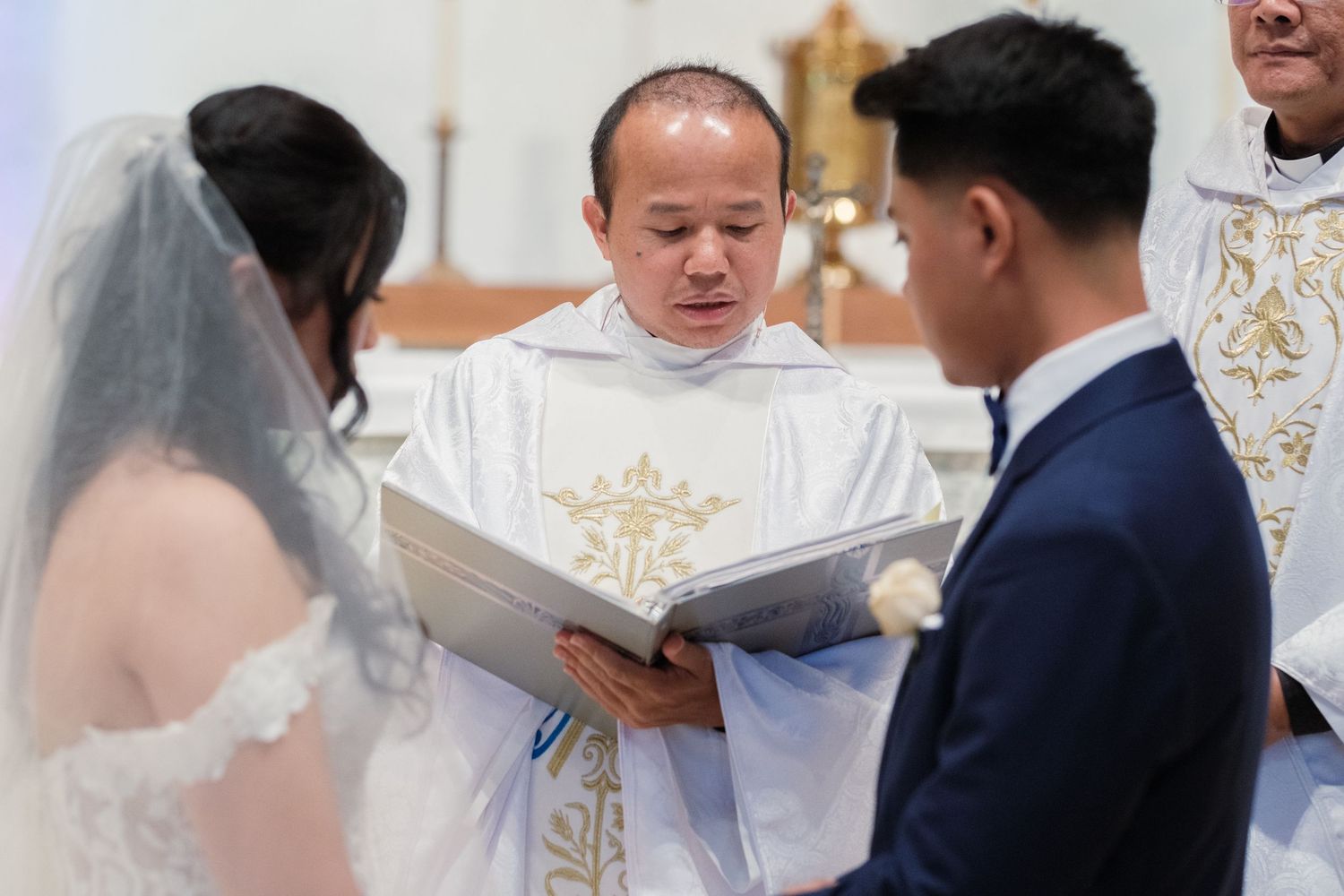 A traditional Catholic wedding ceremony being performed at a church altar with gold decorative elements.