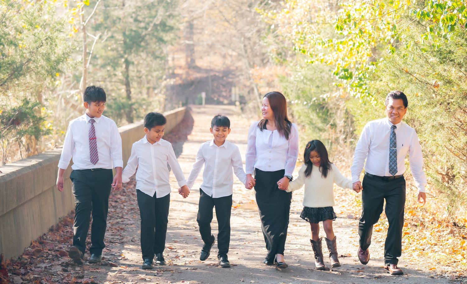 Panoramic outdoor family photo with members walking together in formal attire.