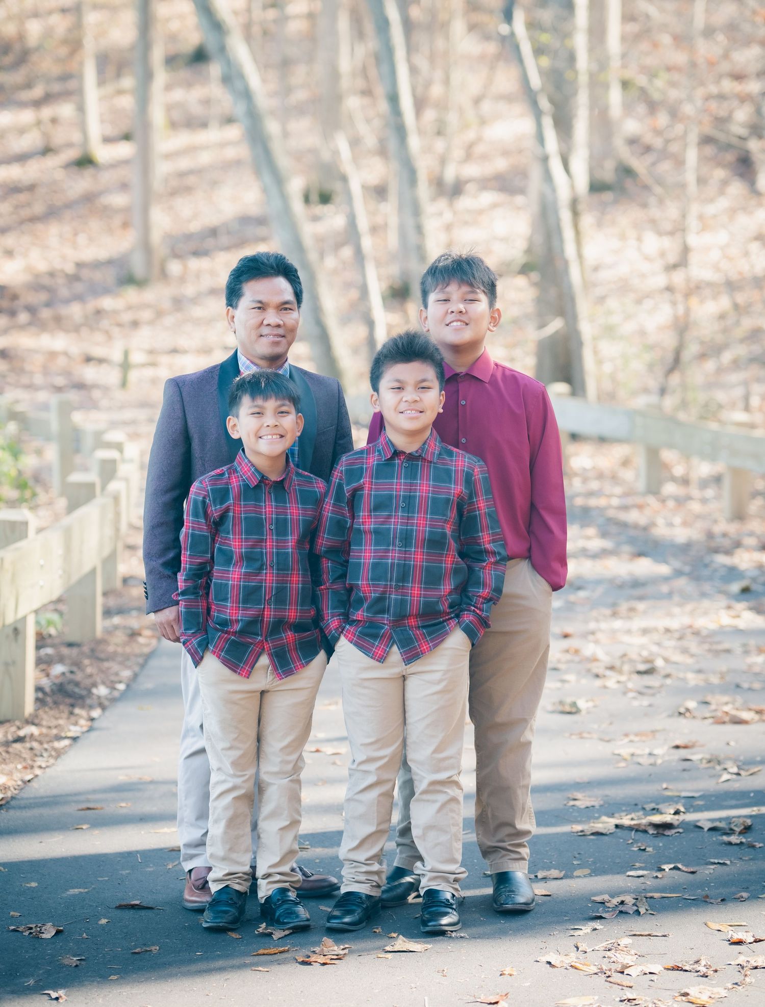 People in coordinated plaid shirts and khakis walk along a leaf-strewn path in the woods.