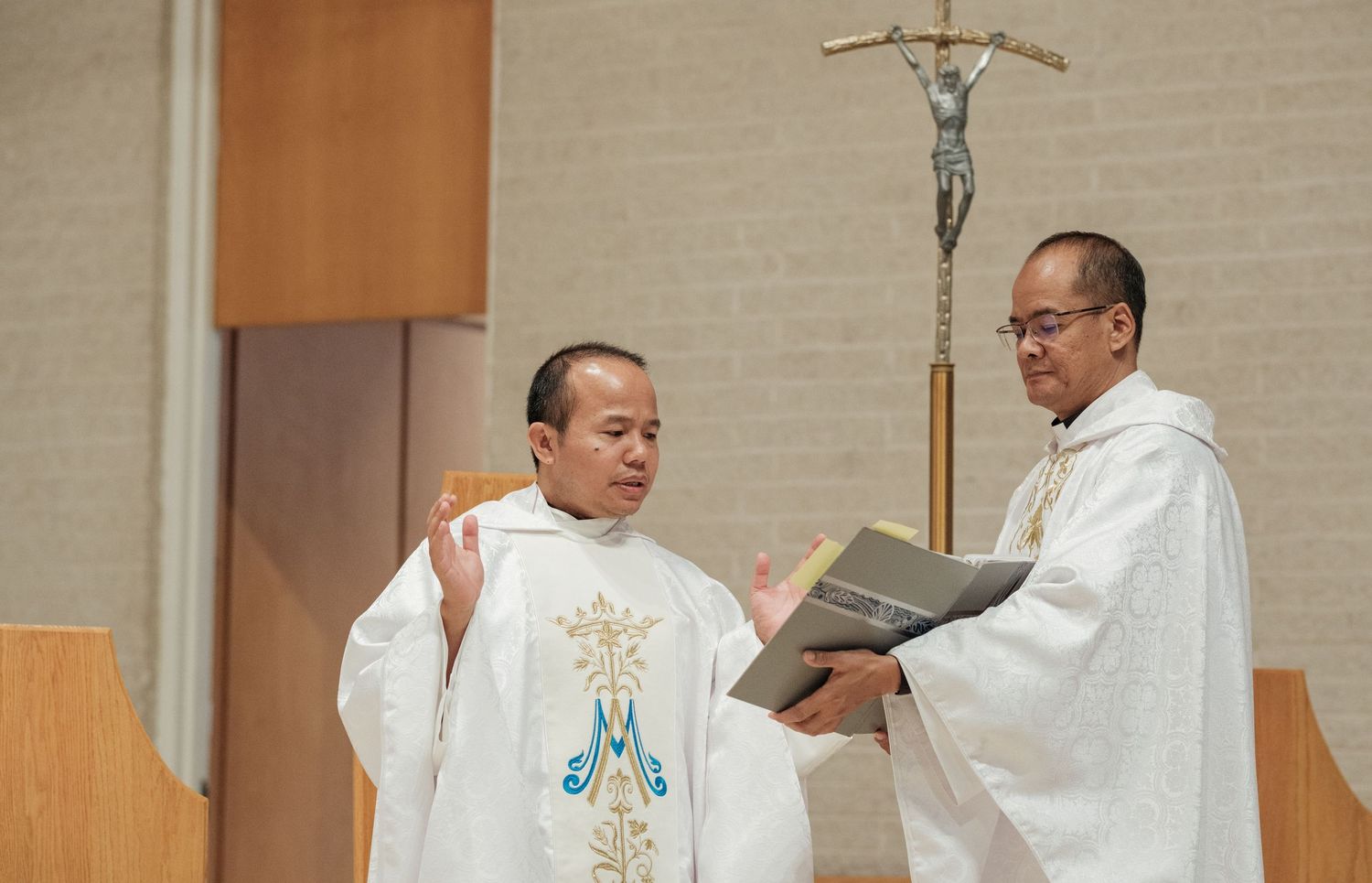 A priest in white robes conducts a religious ceremony at the altar during a church service.