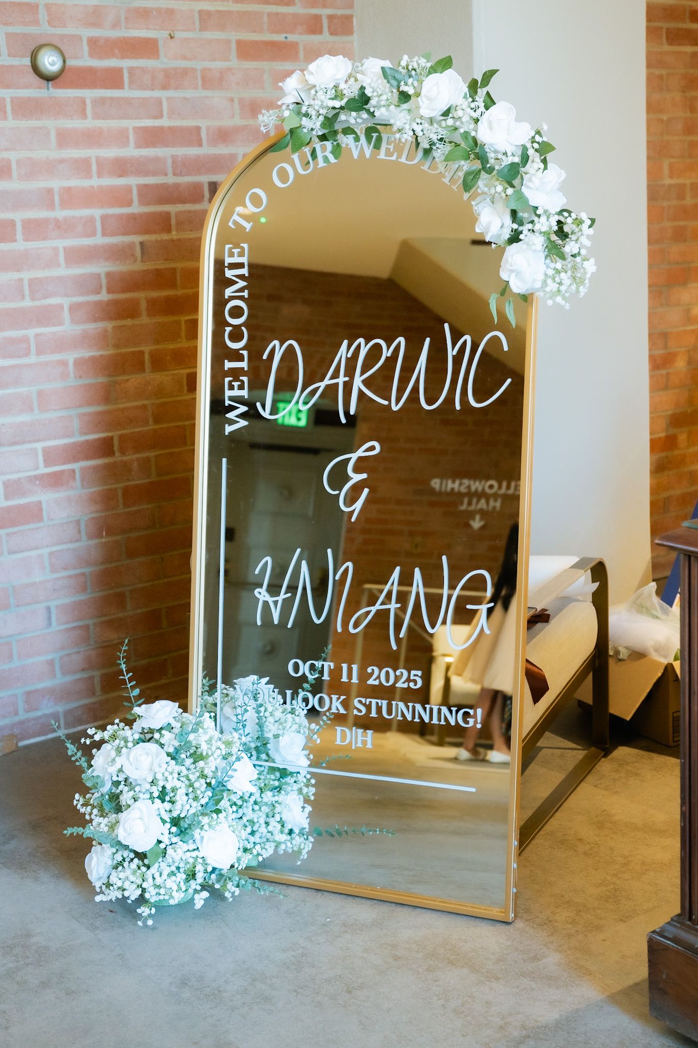 Gold arch mirror wedding welcome sign for Darwic & Hmiang, Oct 11 2025, adorned with white roses and greenery.