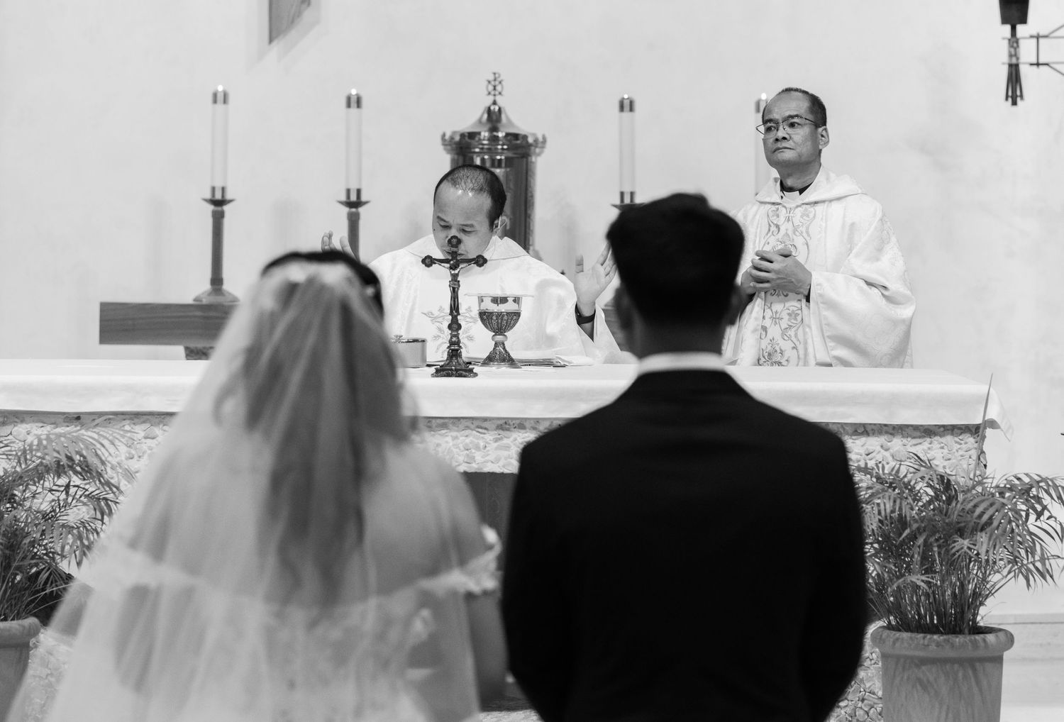 A black and white photo of a wedding ceremony taking place at a church altar.
