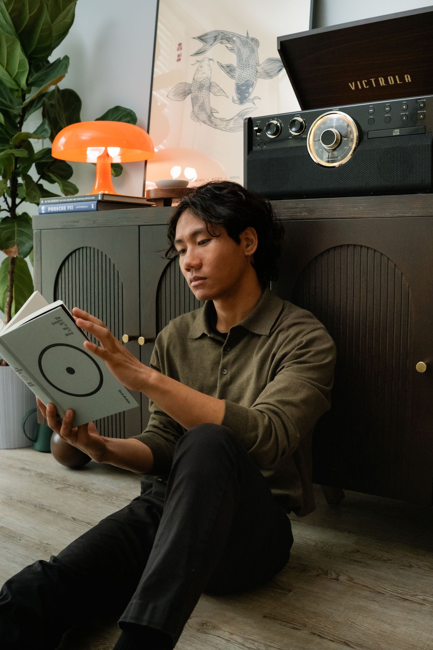Person in casual attire posing with record player and decorative items in home setting.