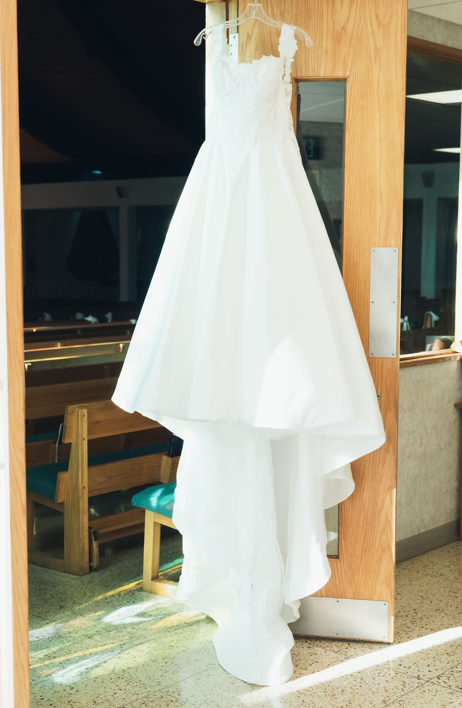 White wedding dresses hanging on wooden display panels in a bridal shop.