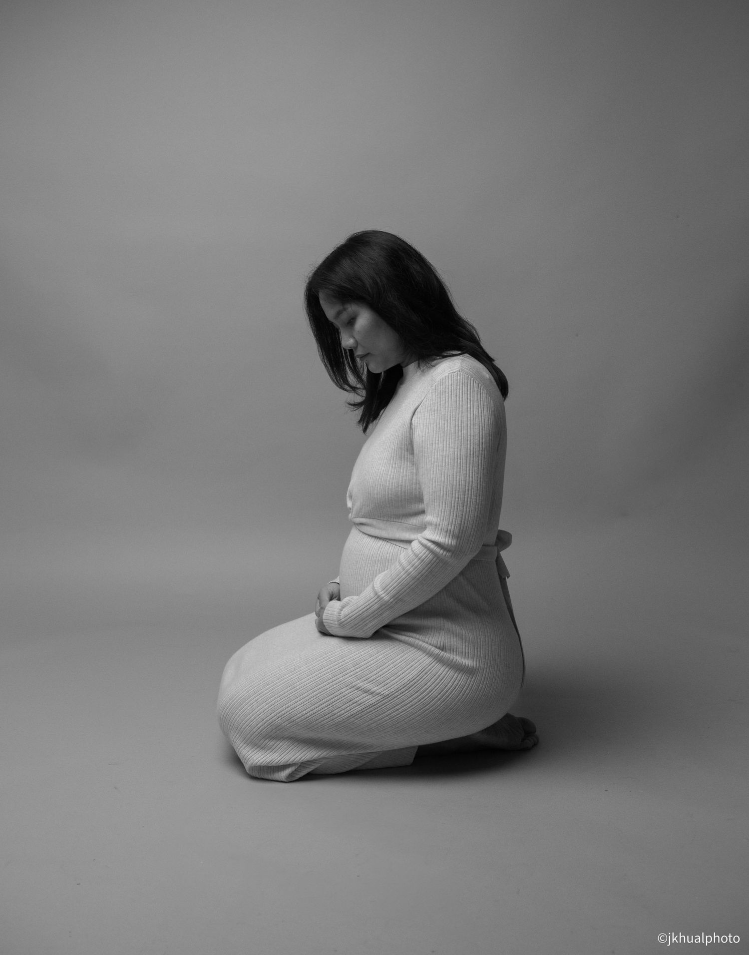 Black and white artistic maternity photo series showing a pregnant woman in various seated poses against a plain background.