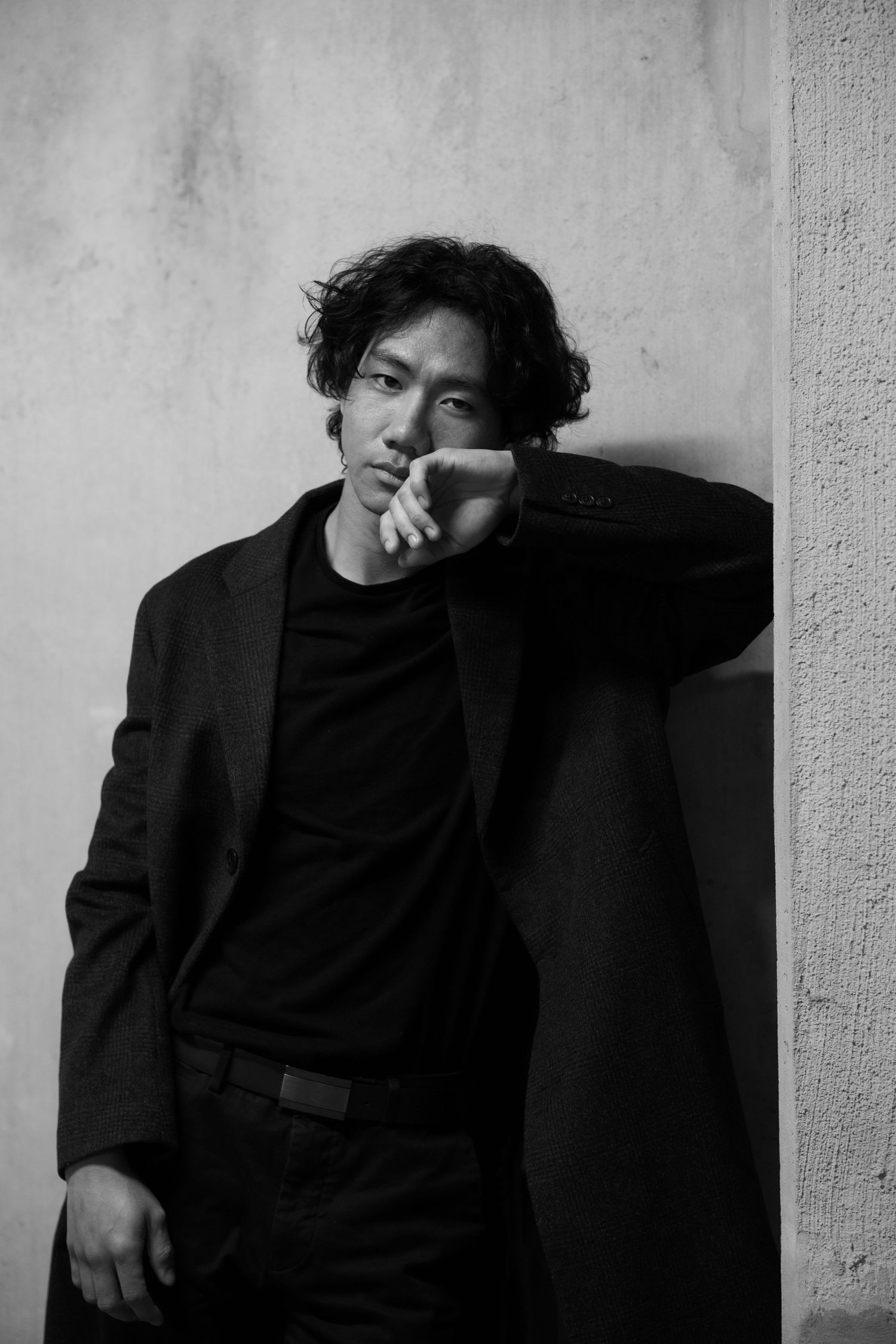 Dramatic black and white portrait against textured wall.