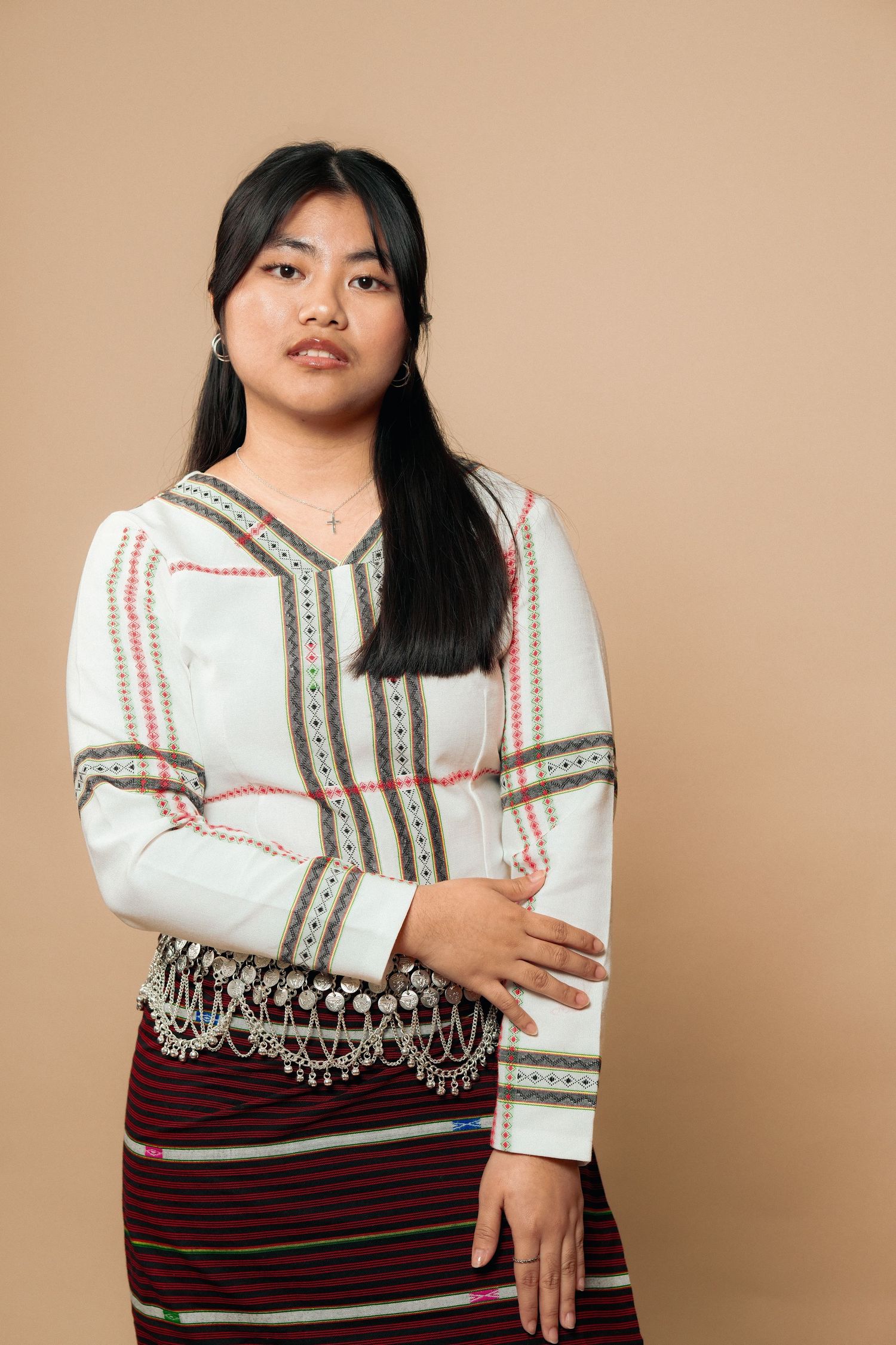 Model in white embroidered top and burgundy traditional skirt poses elegantly.