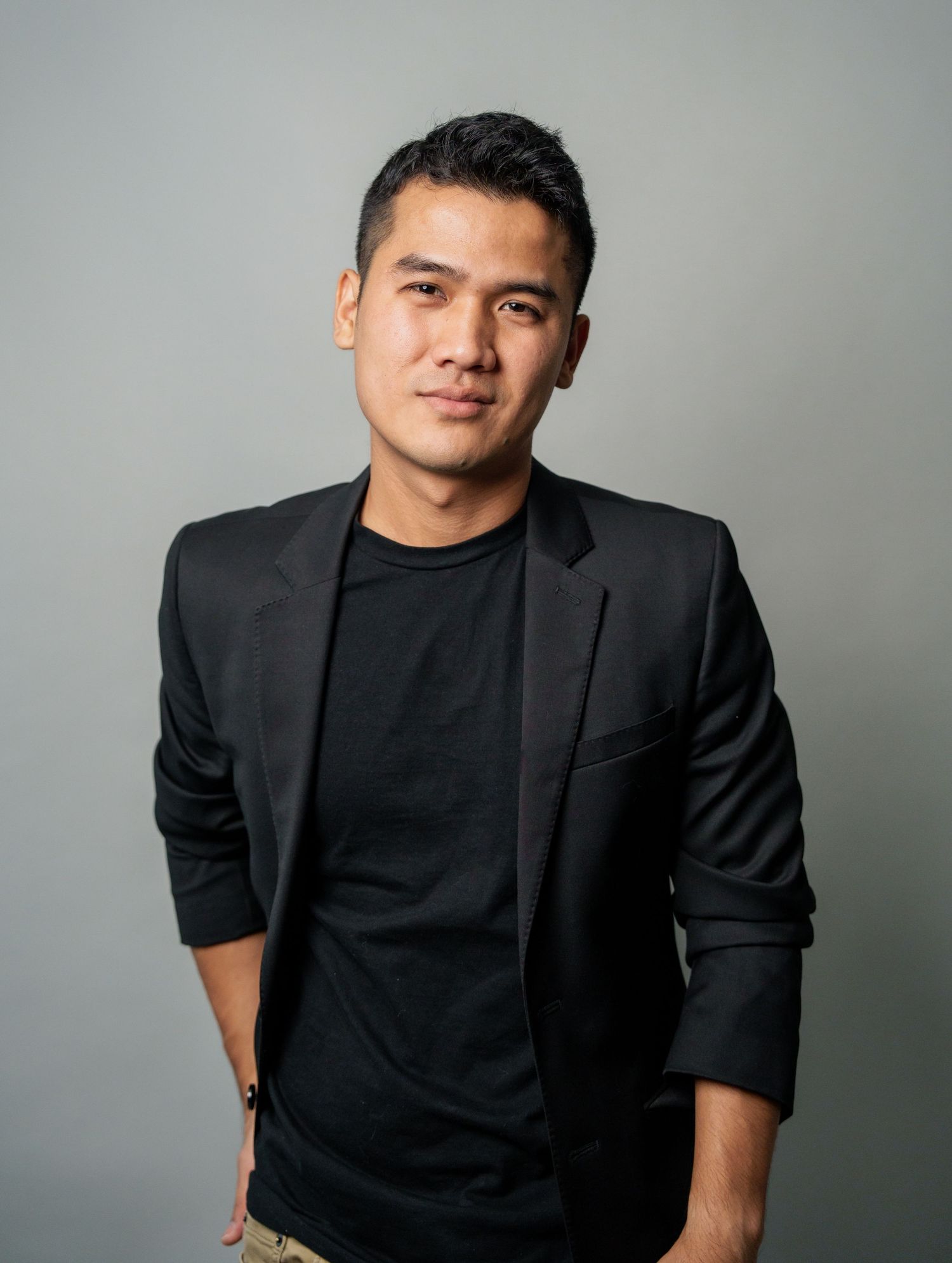 Modern business portrait in black blazer against neutral background.