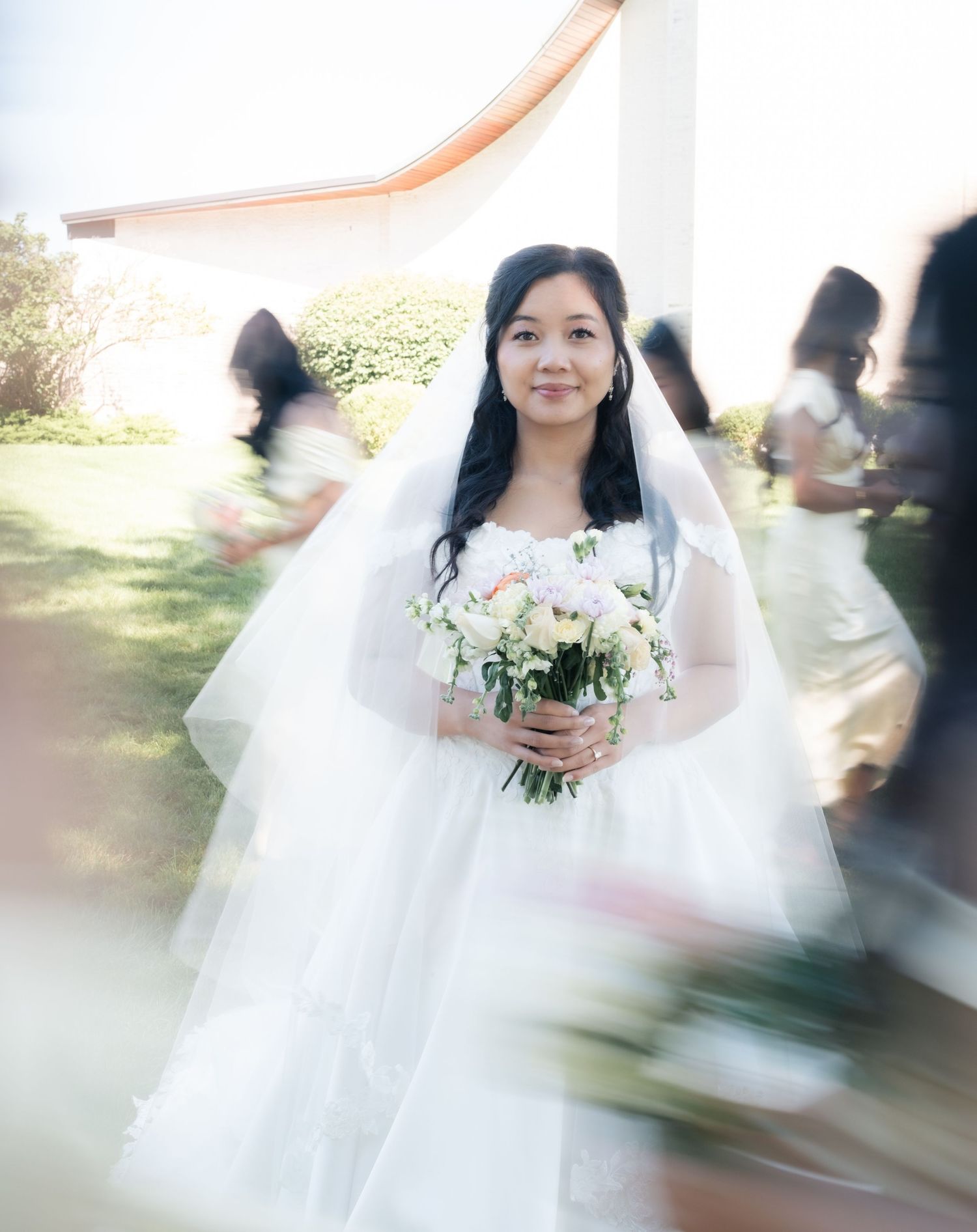 Ethereal bridal portrait with motion blur effect showing bride in white gown holding bouquet.