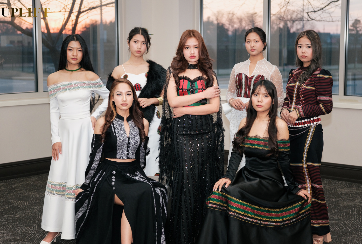 Group poses together in stylish black and white outfits against an indoor setting during sunset hours.