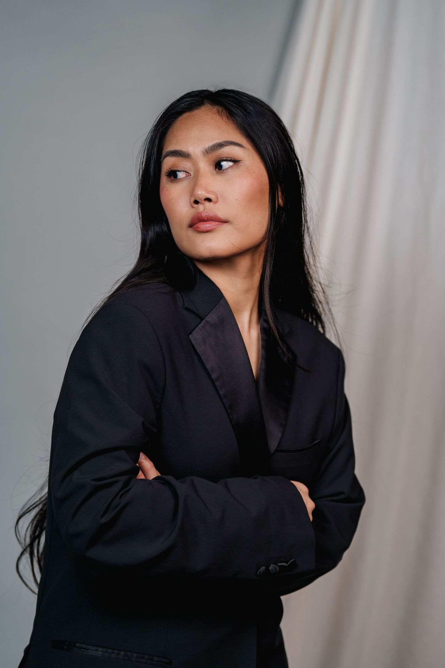 Artistic black and white portrait series featuring dramatic poses in a black blazer against a gray backdrop.
