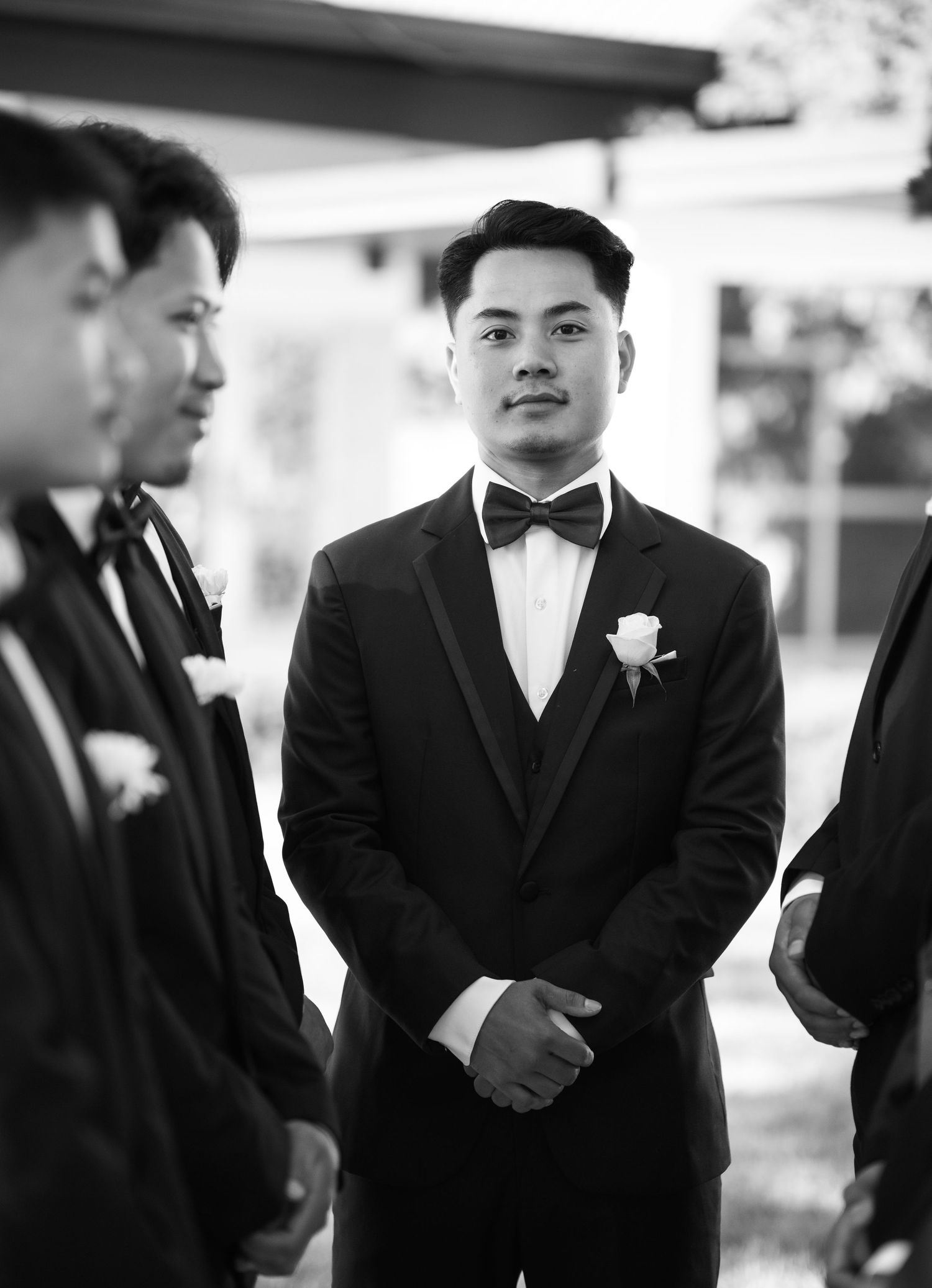 Wedding party members in formal black attire stand in a row.