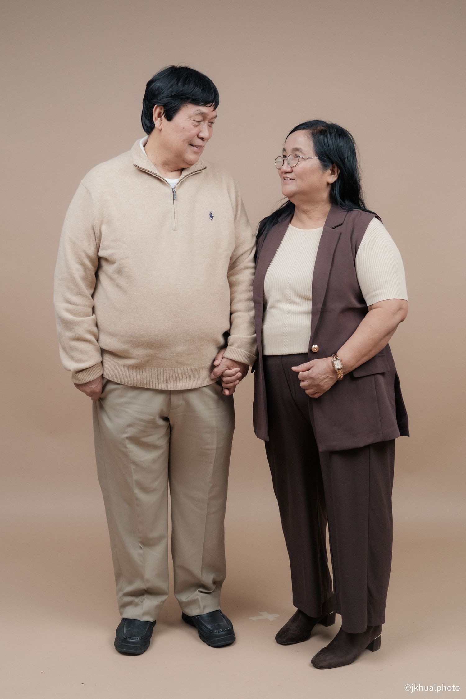 A couple holding hands while standing together in coordinated casual outfits.