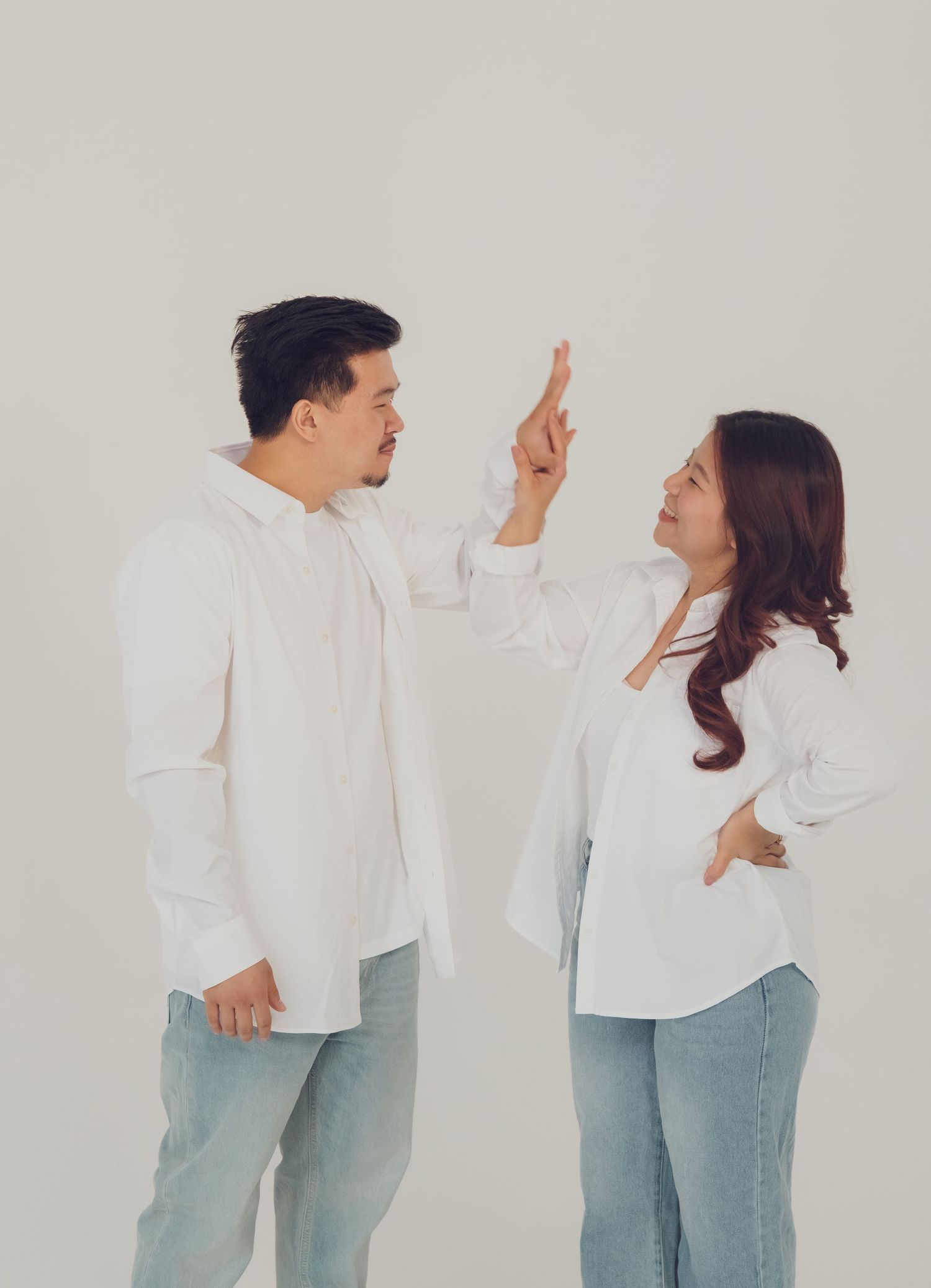 A couple in matching casual outfits gestures animatedly during a photoshoot.
