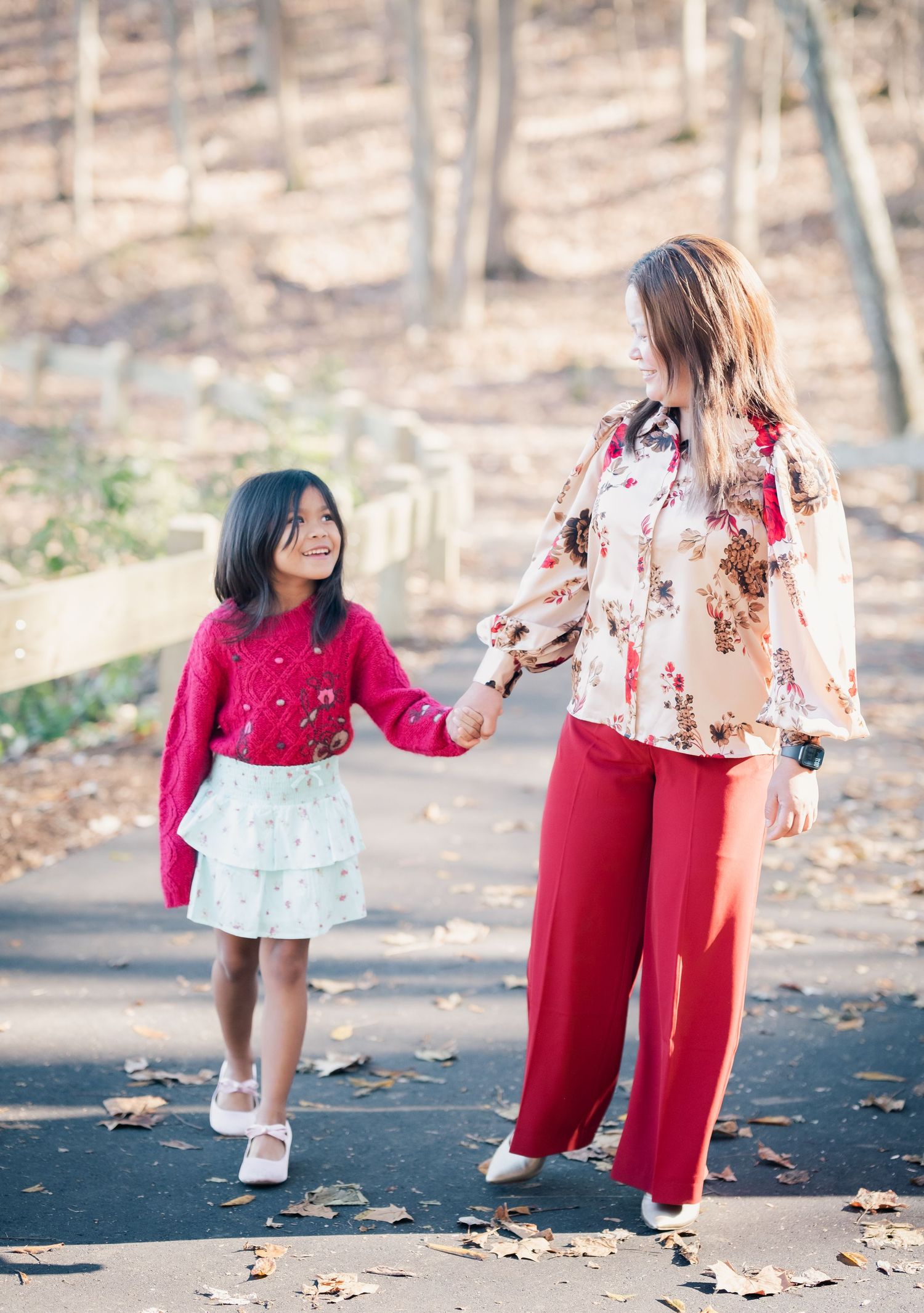 People in coordinating red outfits share a joyful moment on an autumn path.