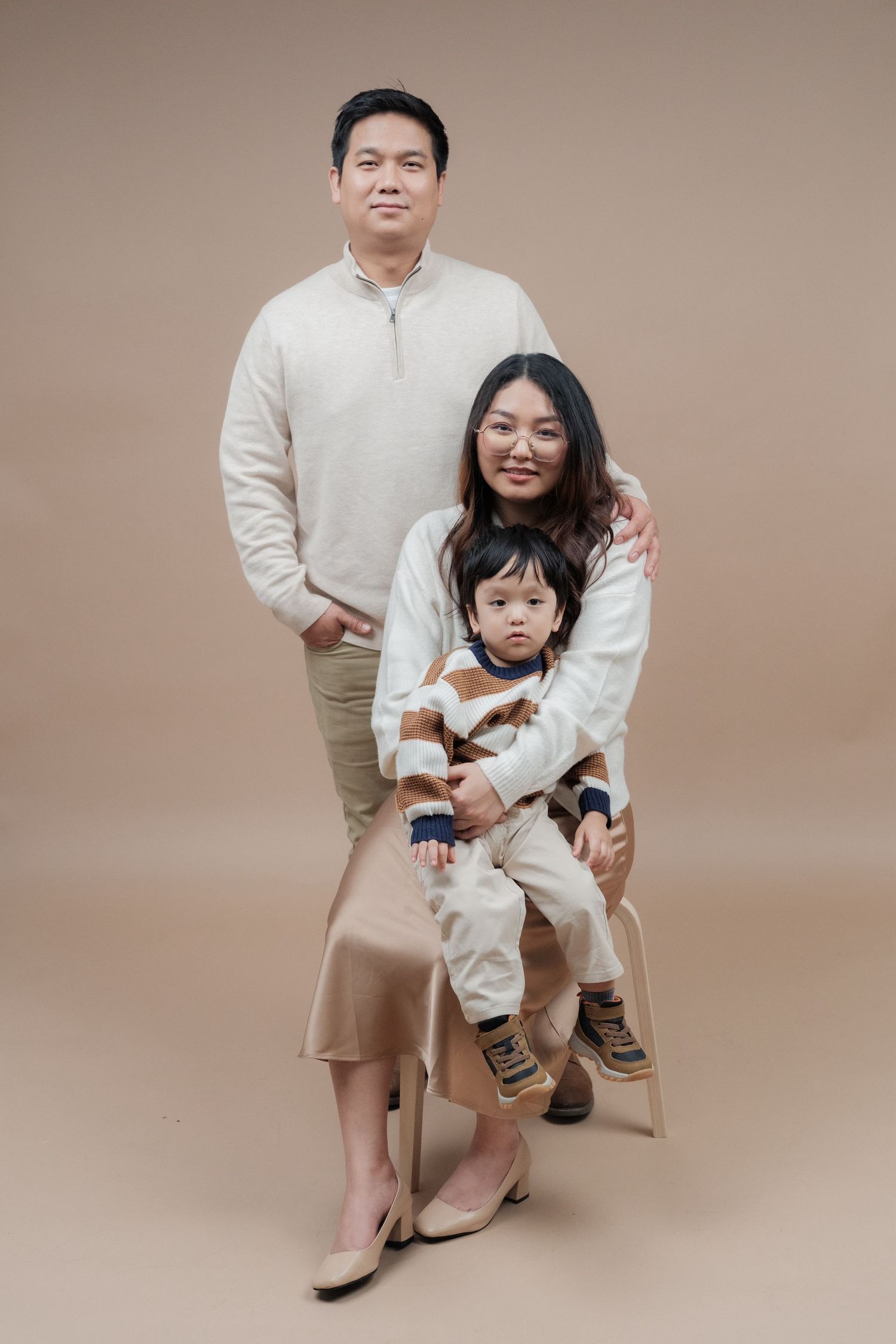 Studio family portraits showing intimate moments in matching cream-colored clothing.