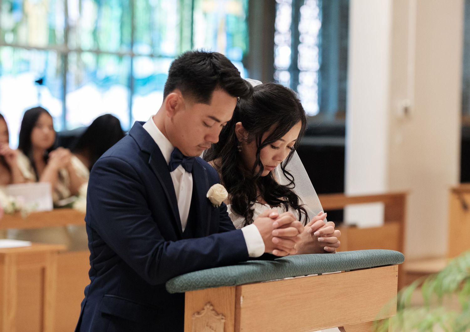 Wedding guests seated in wooden pews during an indoor church ceremony.