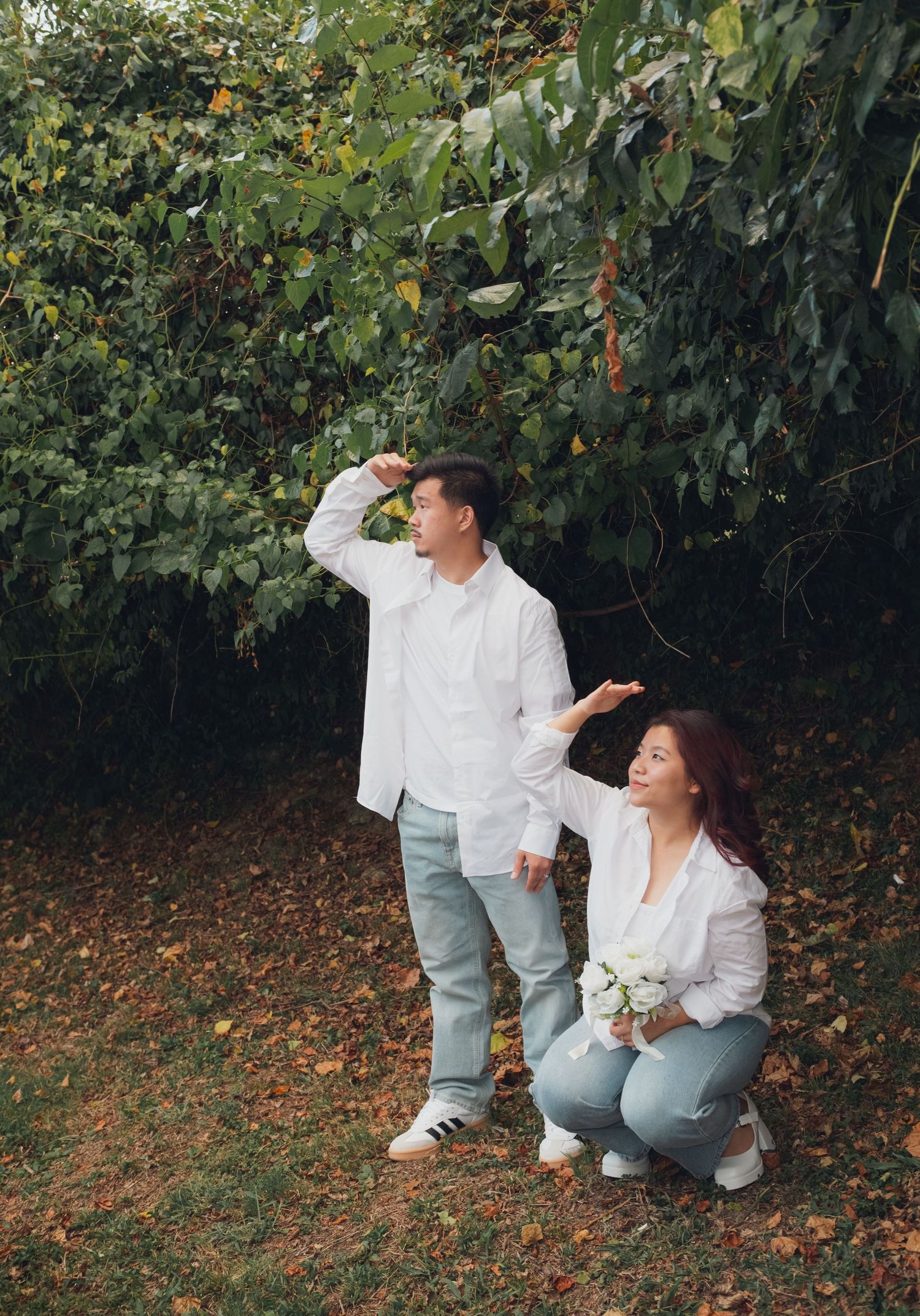 Couple in matching casual wear shares candid moments while sitting on autumn ground.