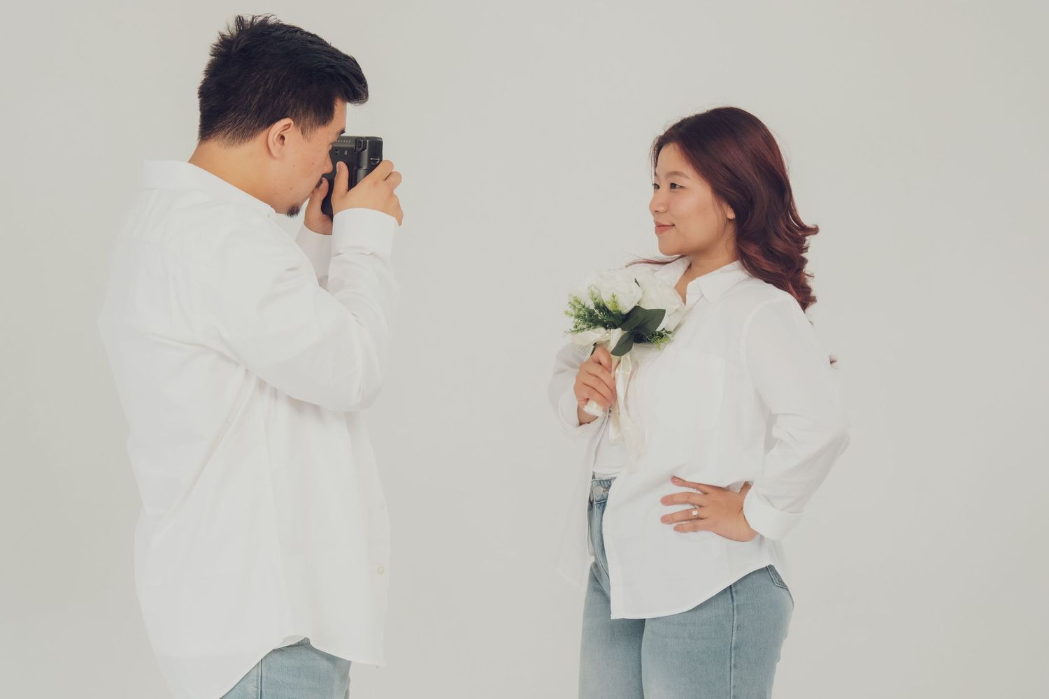 Minimalist studio photoshoot featuring couple in matching white and denim outfits.