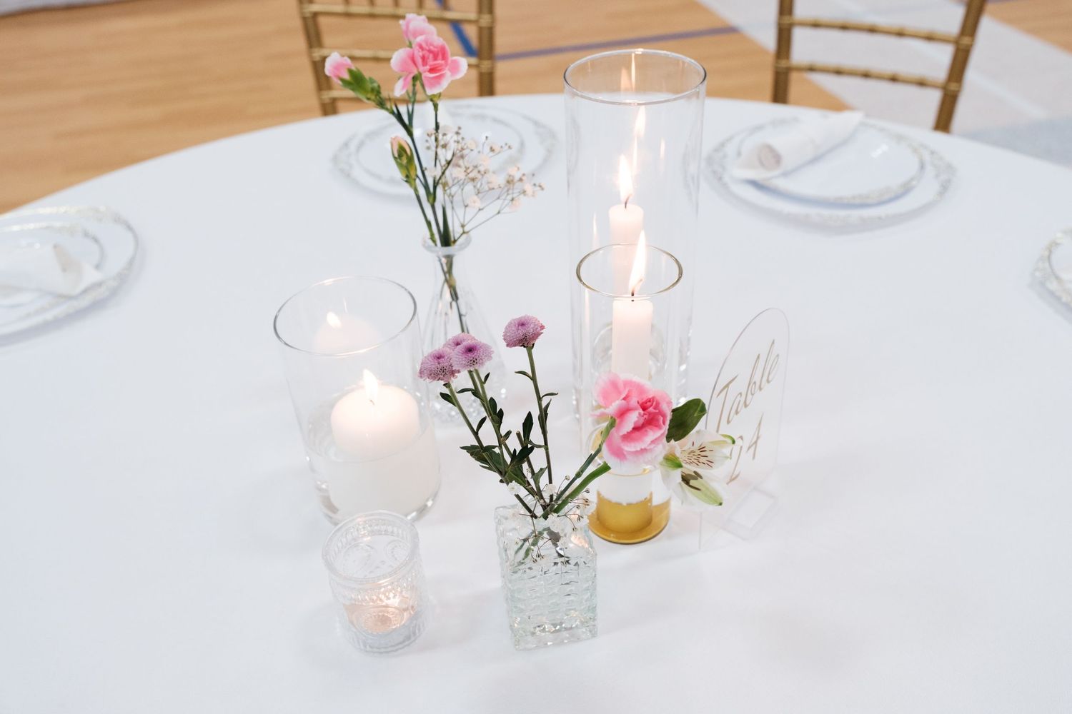 Romantic table setting with glowing candles and pink floral centerpieces.