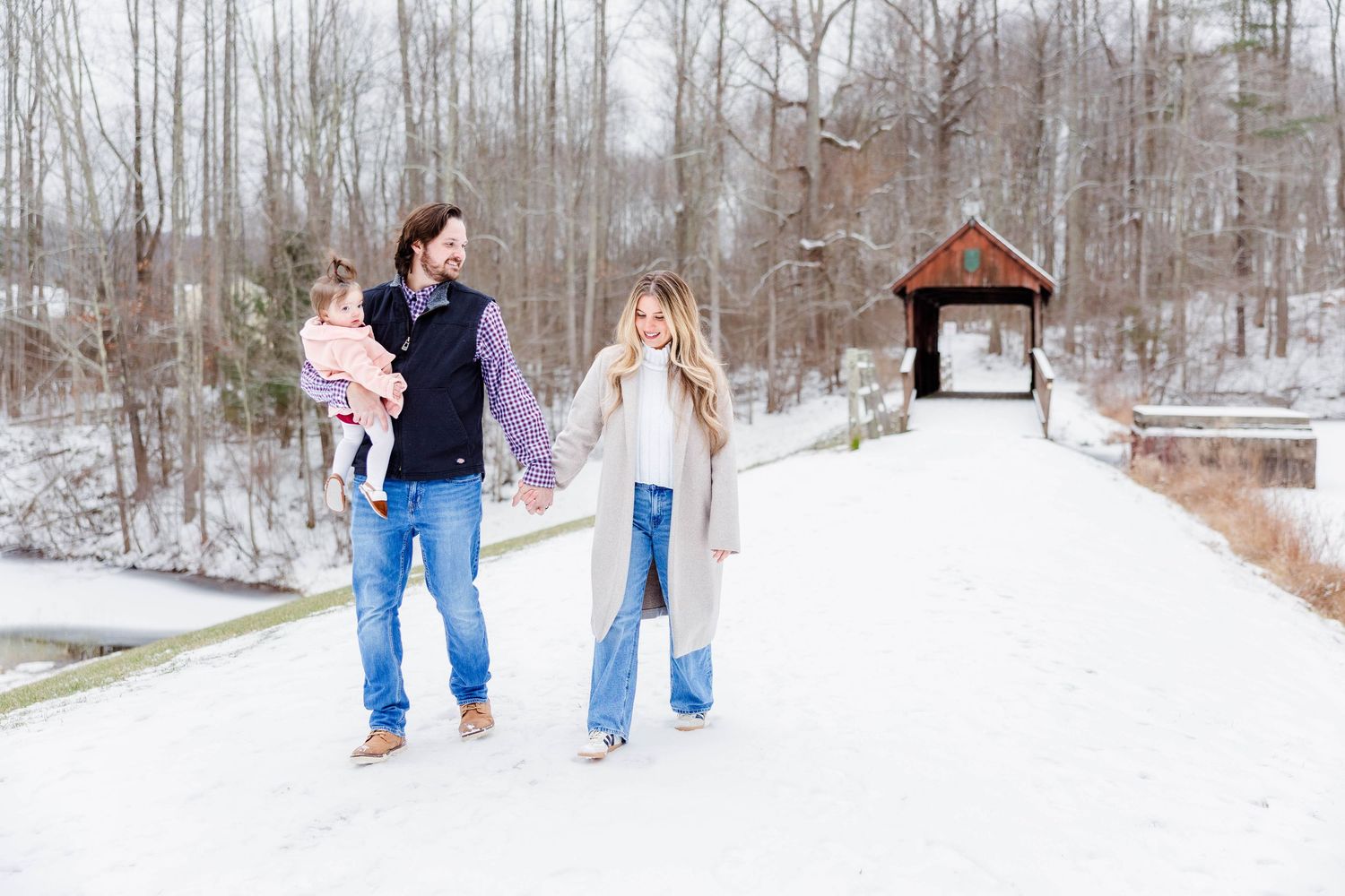 Mom and dad holding hands with daughter between them on a Connecticut walking trail — Minmo Photography