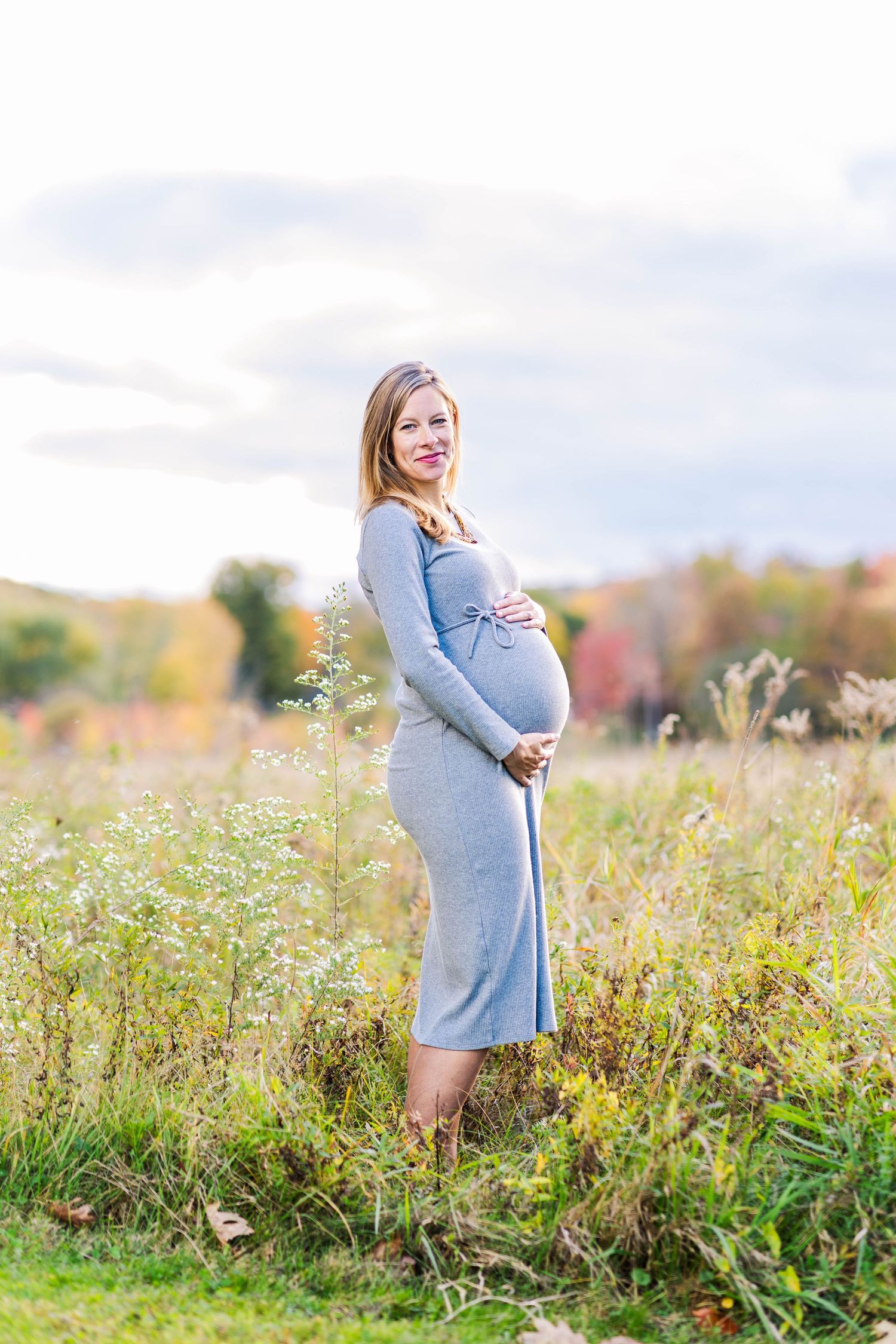 Pregnant woman cradling her belly during a Connecticut maternity session in fall — Minmo Photography