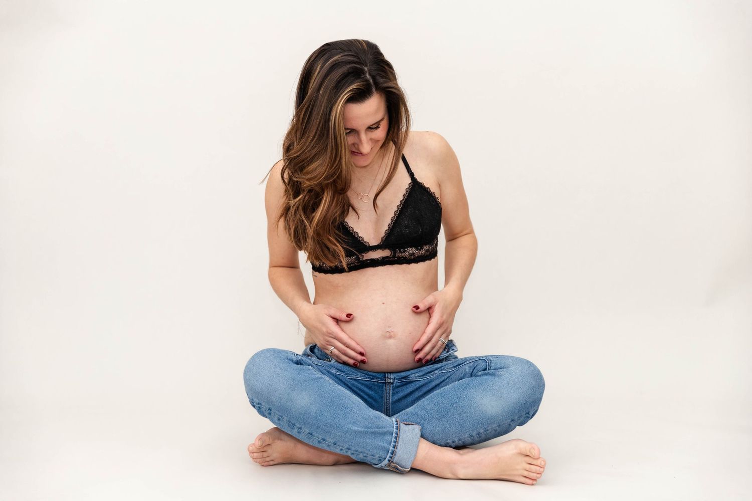 Pregnant woman cradling her belly during a Connecticut maternity session with studio backdrop — Minmo Photography