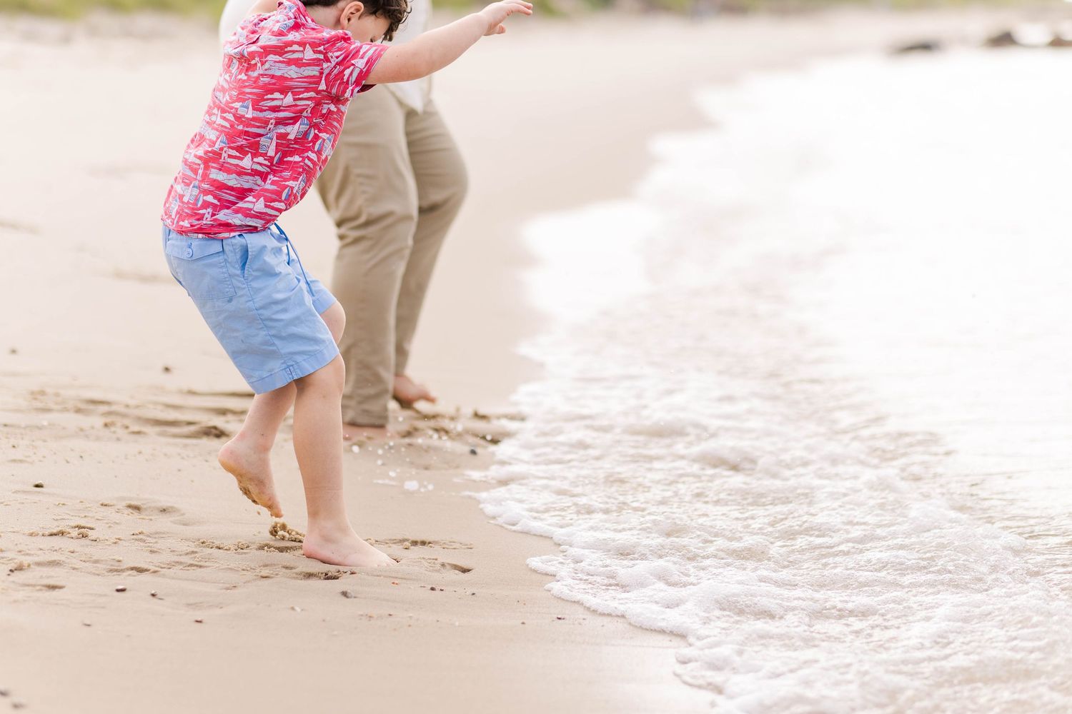 A close-up of a young boy playing tag with the waves at the Connecticut shore -- Minmo Photography
