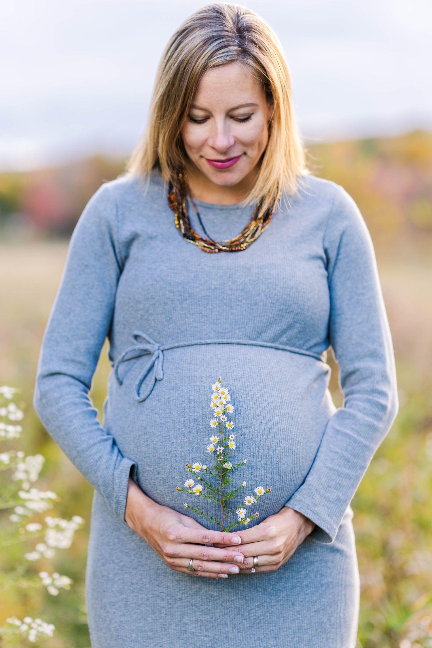 Close-up of pregnant belly with flowers during a golden hour Connecticut maternity session — Minmo Photography