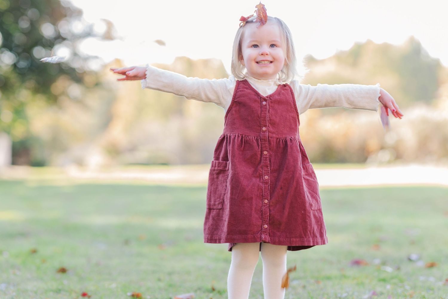 Young woman laughing and throwing leaves during a relaxed Connecticut portrait session in natural light — Minmo Photography