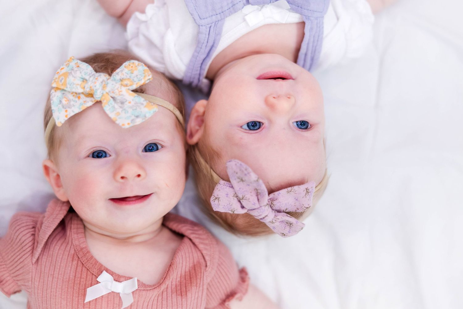 Newborn twins laying on a blanket and looking up at camera during at-home newborn session -- Minmo Photography