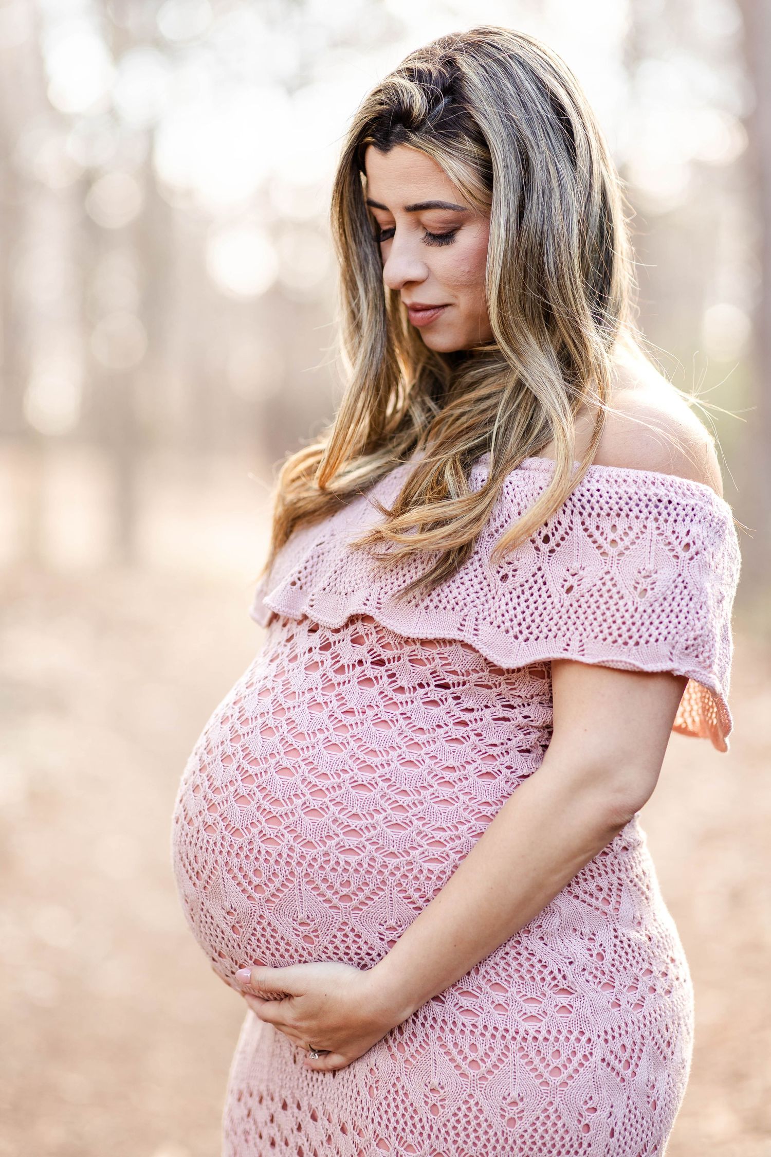 Pregnant woman cradling her belly during a Connecticut maternity session in natural light — Minmo Photography