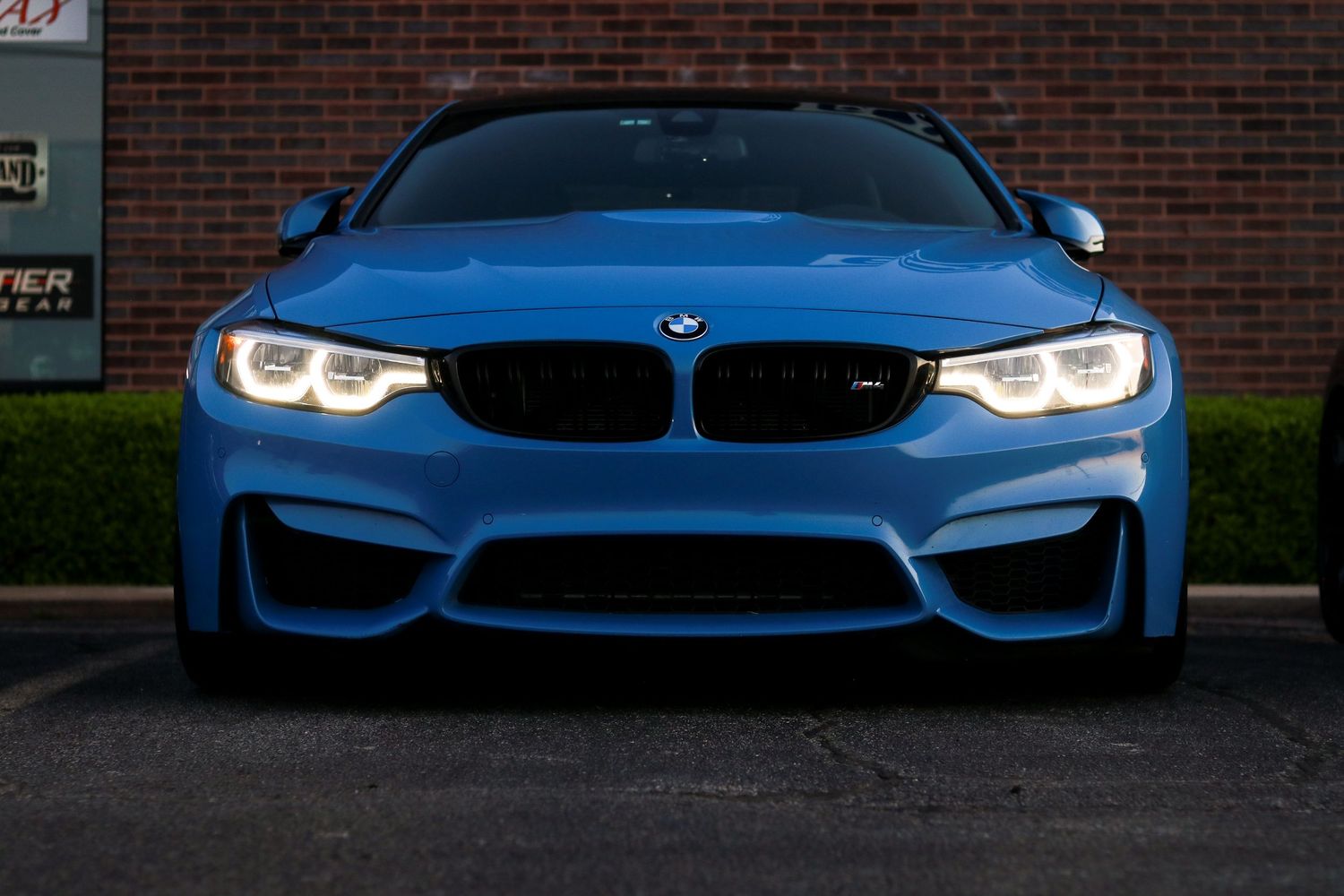 BMW M-series performance cars in blue displayed against brick building at night.