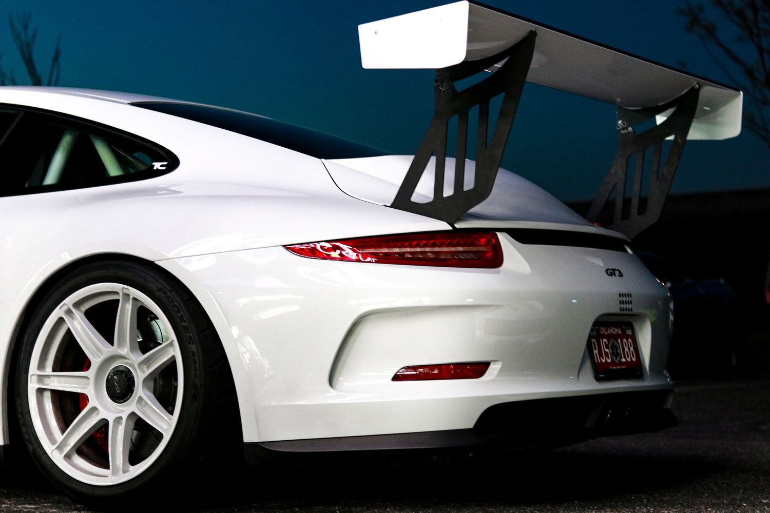 Artistic silhouette shots of a white Porsche 911's rear profile at dusk.