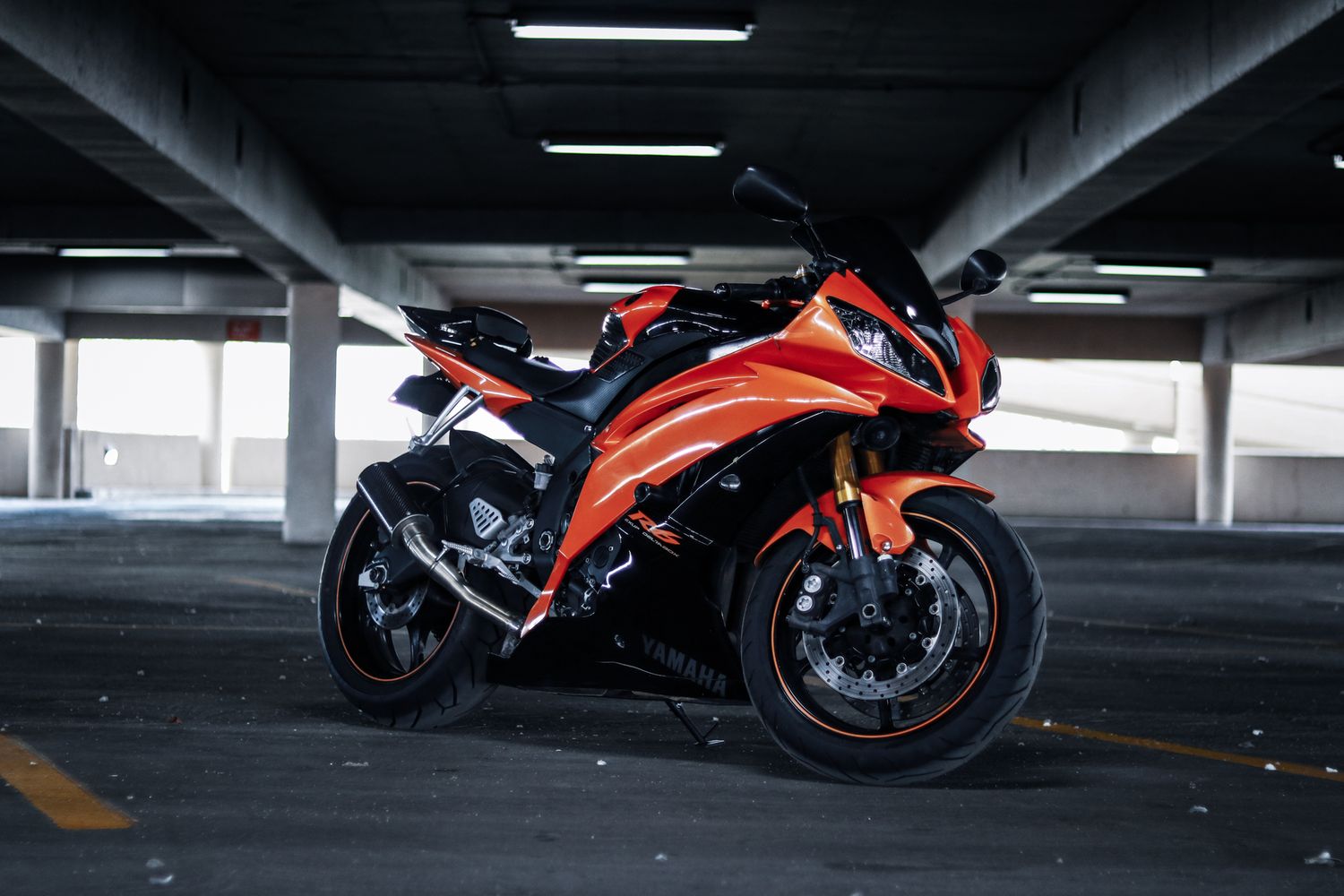 Orange and black Yamaha R6 lined up in an indoor parking structure.