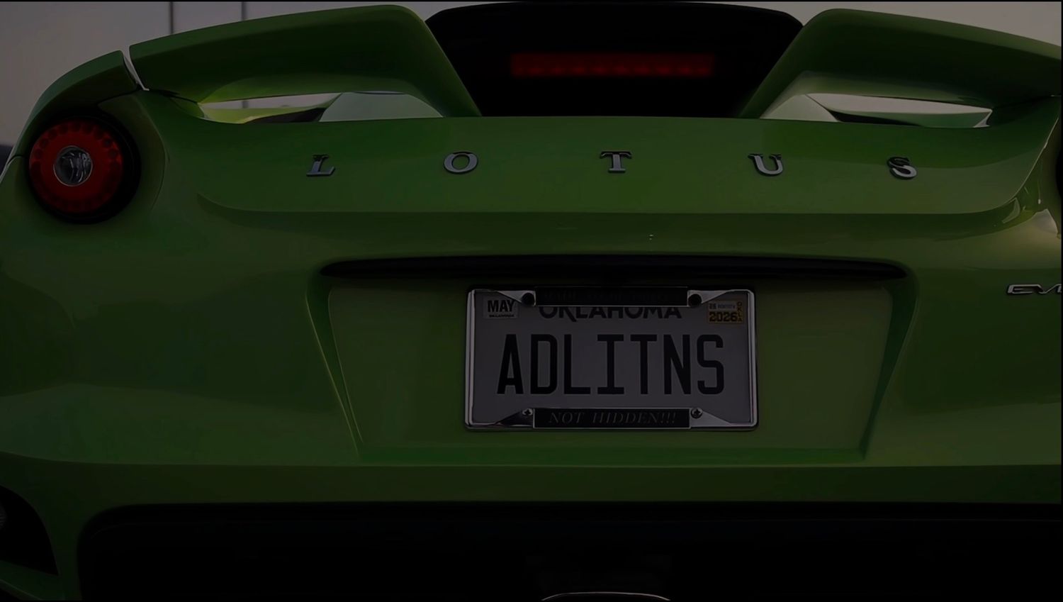 Close-up view of a green sports car's rear end showing a custom license plate that reads WDLTNS.