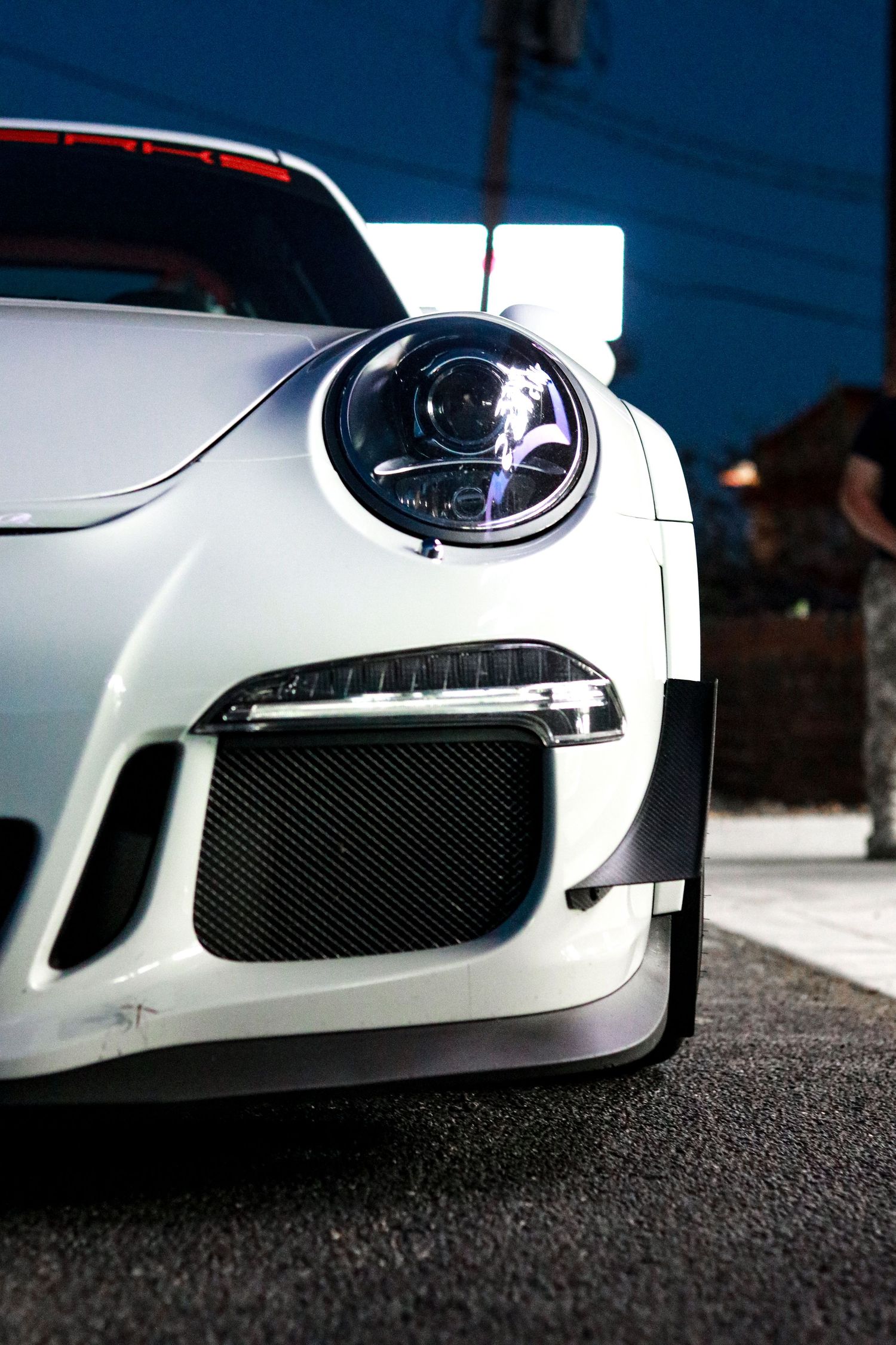 Front end details of a white Porsche GT3 showing headlights and front splitter.